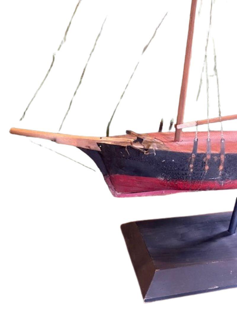 19th Century New England Folk Art Schooner Weathervane, circa 1890, having a carved and painted wooden hull with bowsprit, spars and deck house; wooden masts with wire standing rigging; iron anchors; sheet metal main sail, American flag, and