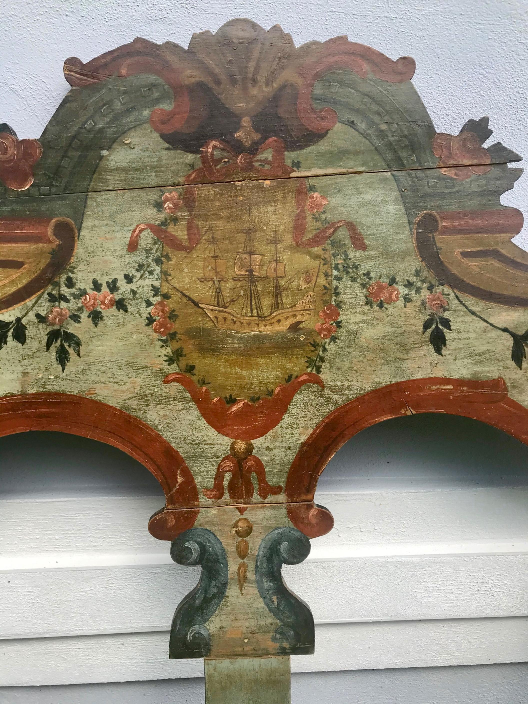 19th century New England hand painted wooden headboard

This beautiful and colorful (twin sized) Baroque style cutout wooden headboard is hand painted. It is a New England piece of cottage furniture. A frigate in a cartouche relates to the