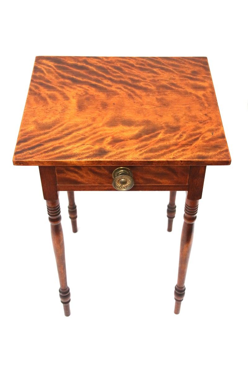 19th century New England Sheraton flame birch one-drawer stand, the highly figured top projecting over one-drawer with brass pull resting on nice ring turned legs.

Dimensions: 27 ¾” H X 19 ¼” W X 17 ¾” D.