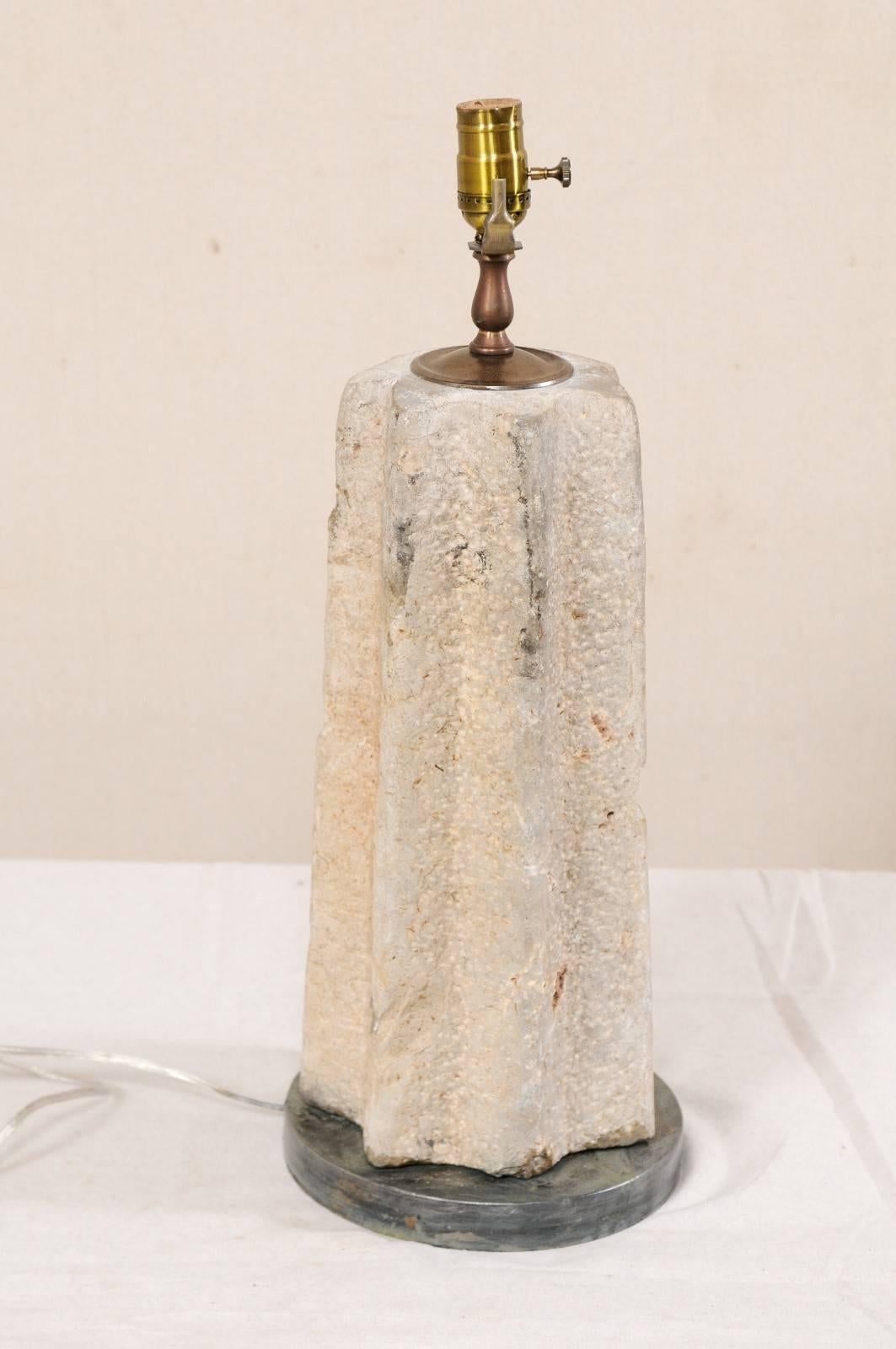 A single custom table lamp from a section of 19th century millstone. This single table lamp has been custom fashioned from a cut section of a 19th century millstone, mounted with it's body tapered more towards the neck, and grinding ridges vertical.
