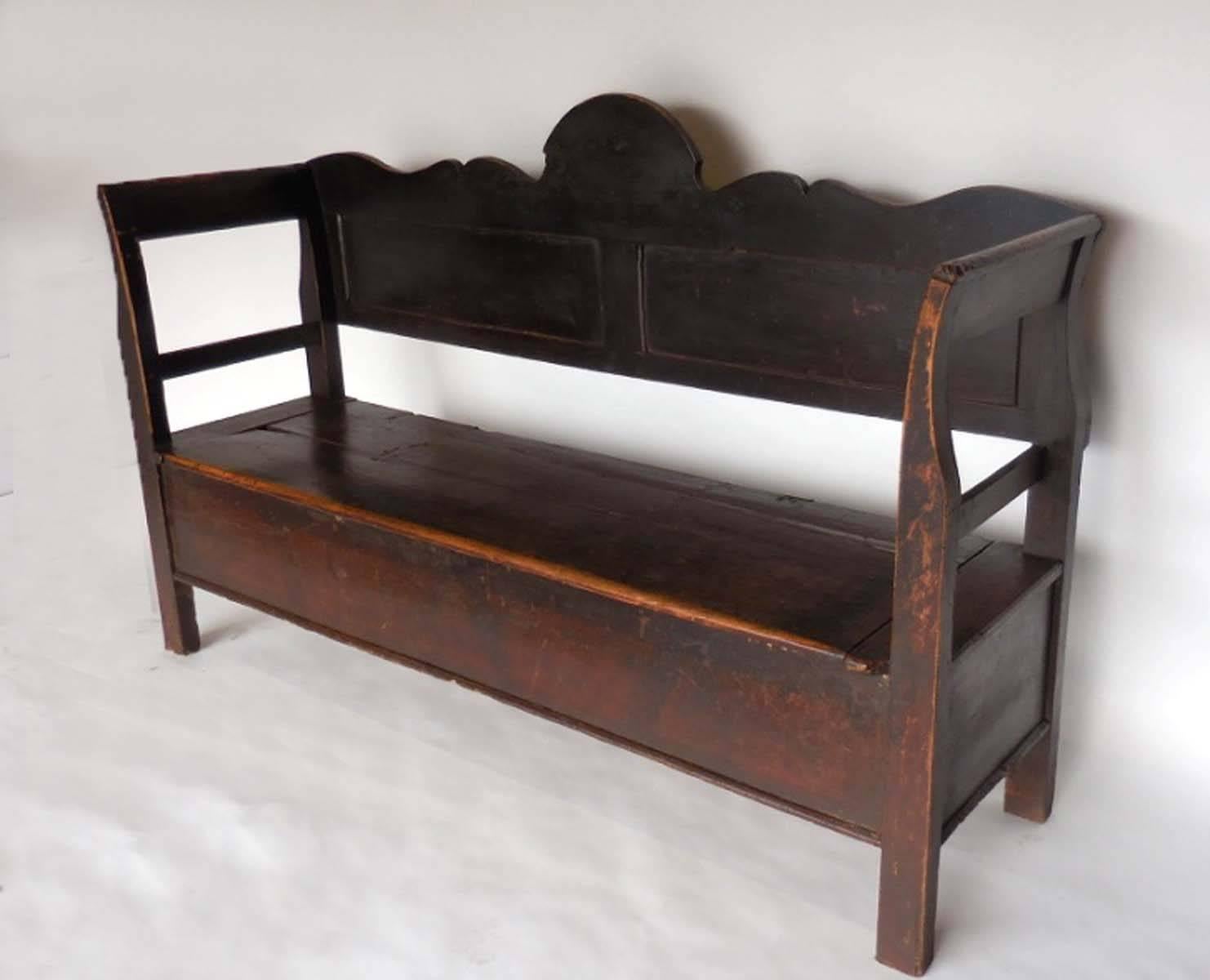Beautiful bench with a sculptural cut-out back and lift top seat for storage. Old worn dark patina with natural wood showing through around edges. Very smooth. Graceful shape. Pine wood.