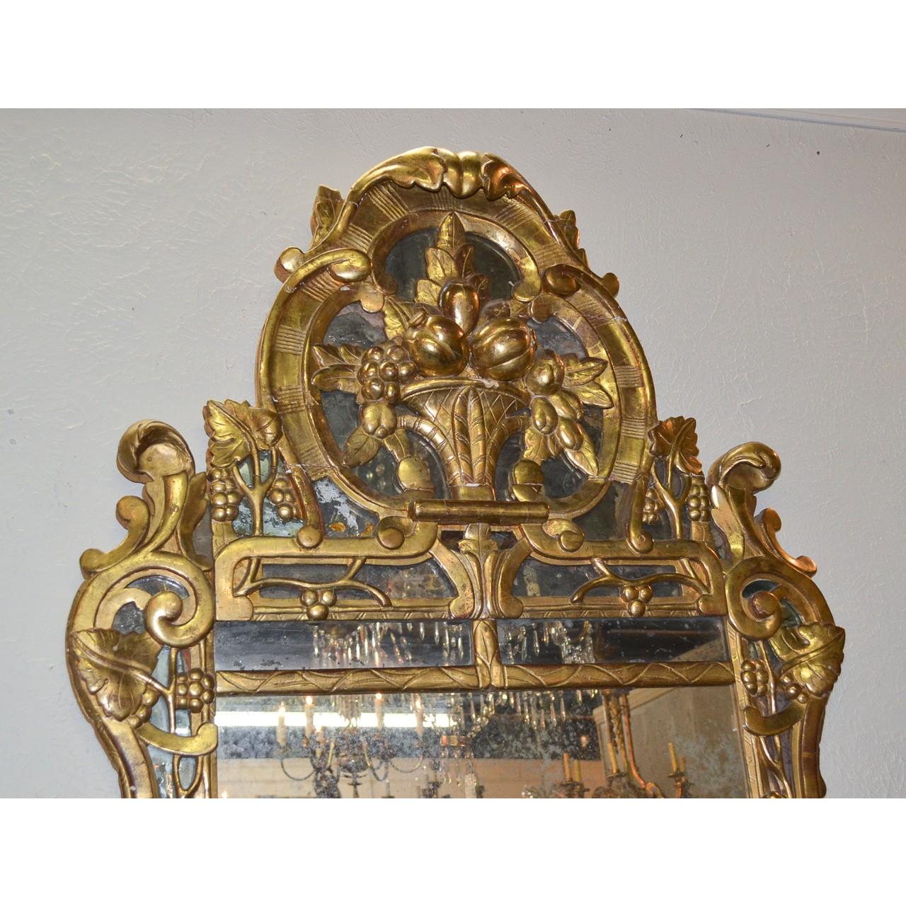 Magnificent 19th century Northern Italian giltwood wall or console mirror. The crest ornately carved and featuring a centre cartouche carved in bas-relief depicting a vessel overflowing with fruits and leaves and flanked by leaf scrolls, grapes and