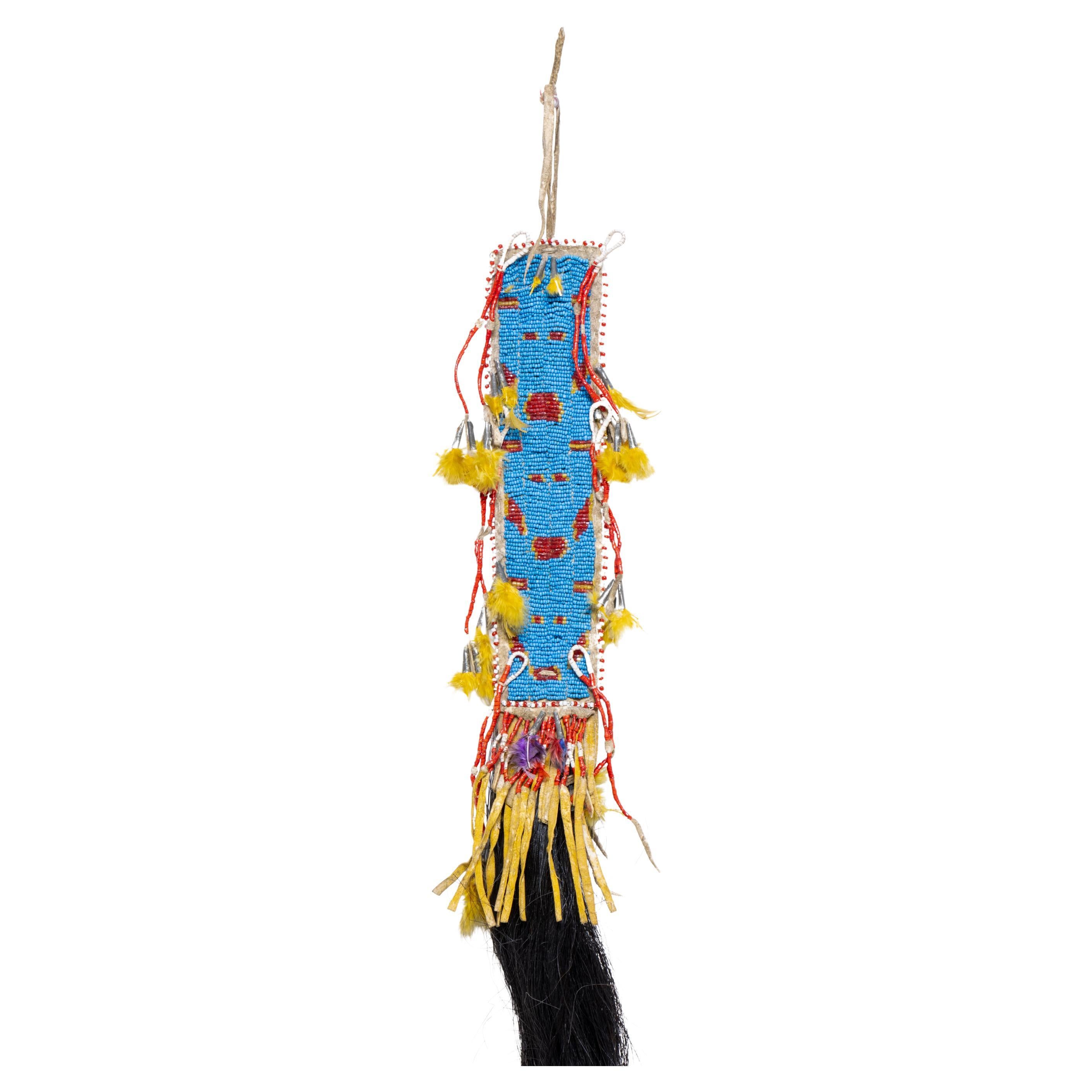 Northern Plains hair drop. Beaded blue with red accents. Quilled drops having tin cones and yellow feather fluffs with long black horsehair drop.

Period:  19th century
Origin: Great Plains - Northern Plains, Native American
Size: 6