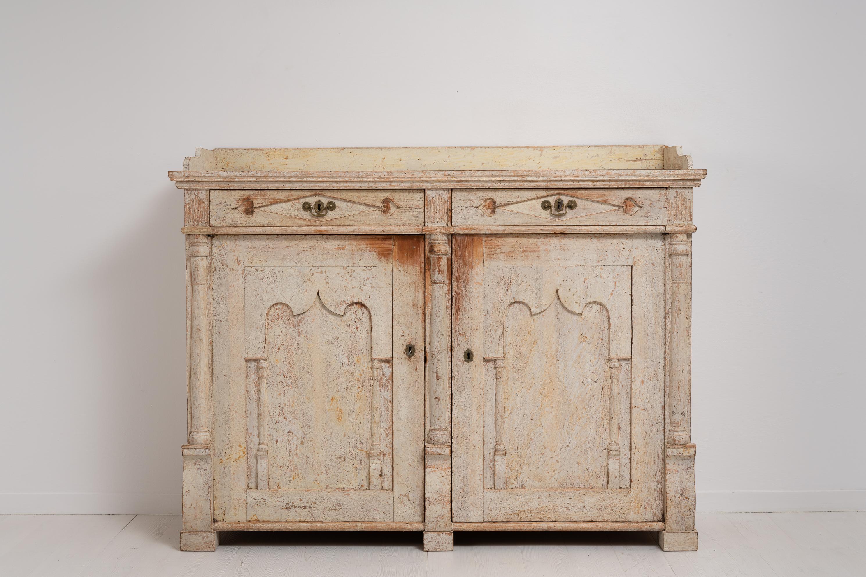 Northern Swedish sideboard from the transitional period between the gustavian and empire era. This unusual sideboard is from around 1820 to 1830. Painted pine dry scraped by hand to the original cream paint with the distress and patina of time.
