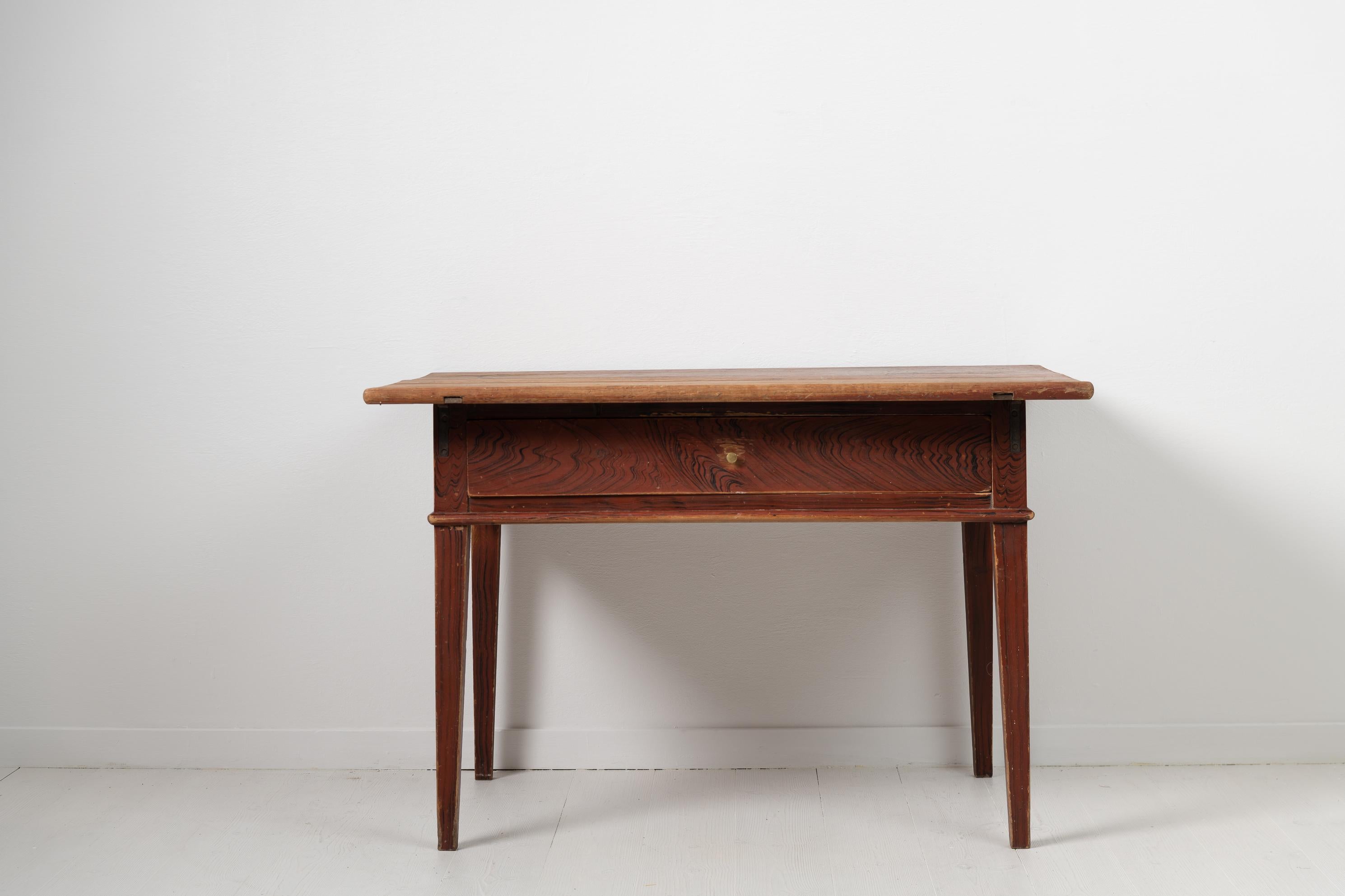 Northern Swedish country side table in gustavian style made during the early 1800s. The table is in untouched original condition with the original faux paint. Made in pine with the original brass handle on the drawer. Natural wear and authentic