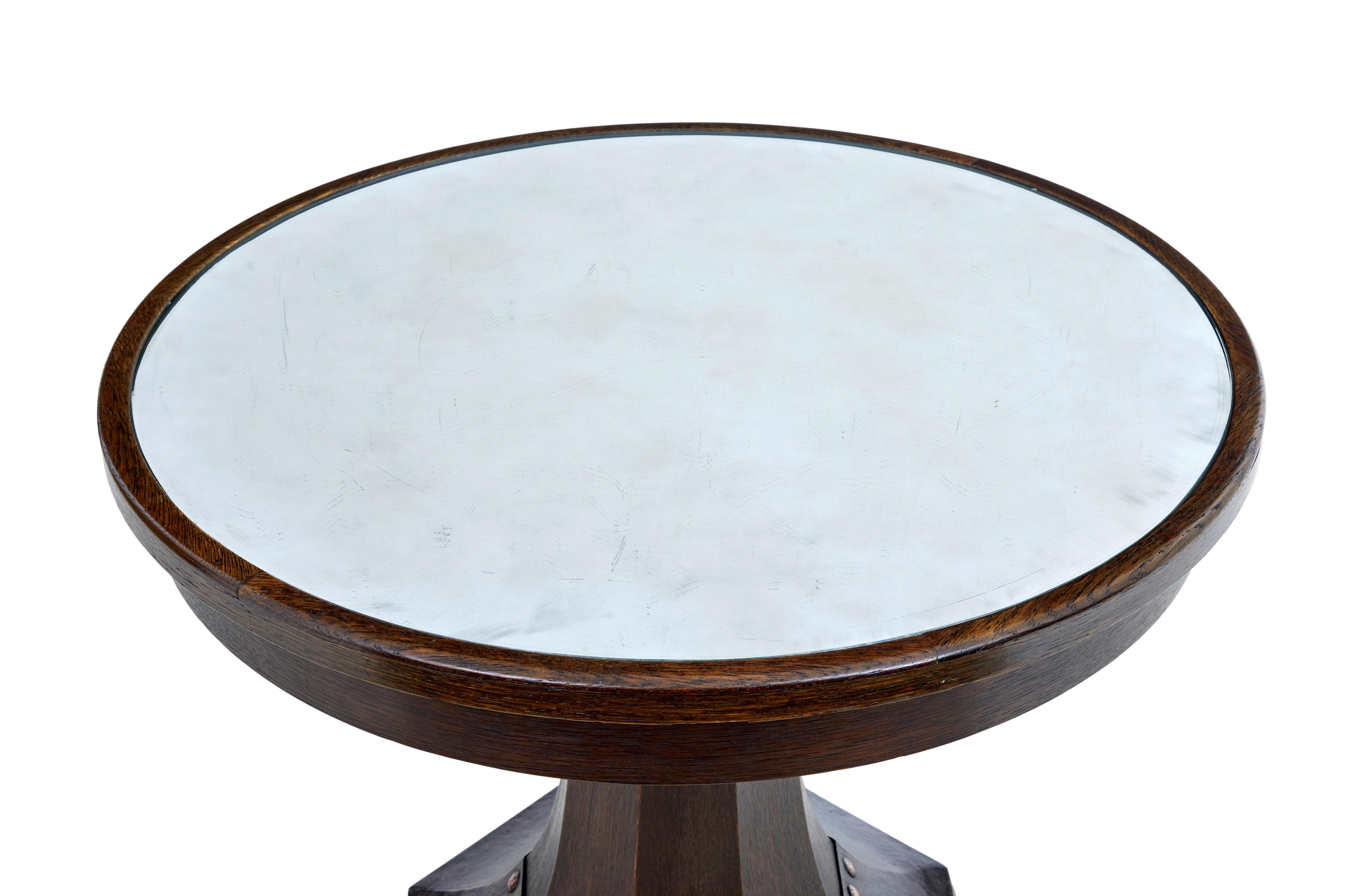 19th century oak and copper aesthetic movement center table circa 1890.

Stickley style pedestal table,  round top with a frosted antique mirror effect on the underside of the glass, with a oak bordered edge.  Octagonal fluted pedestal encased with