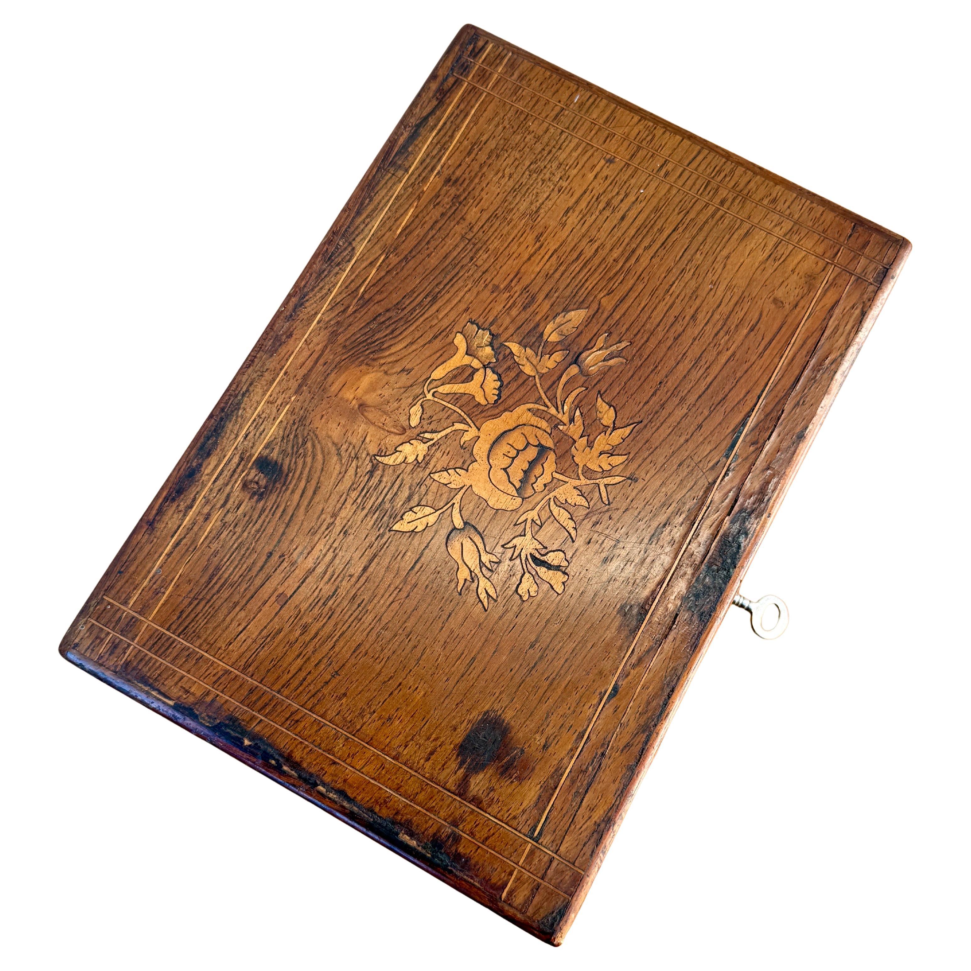 Boîte à bijoux suédoise Biedermeier du XIXe siècle en chêne avec une incrustation ornementale. Le travail d'intarsia fin, présentant un motif floral, est réalisé dans un bois de fruitier plus clair. La boîte est munie d'une serrure et d'une clé