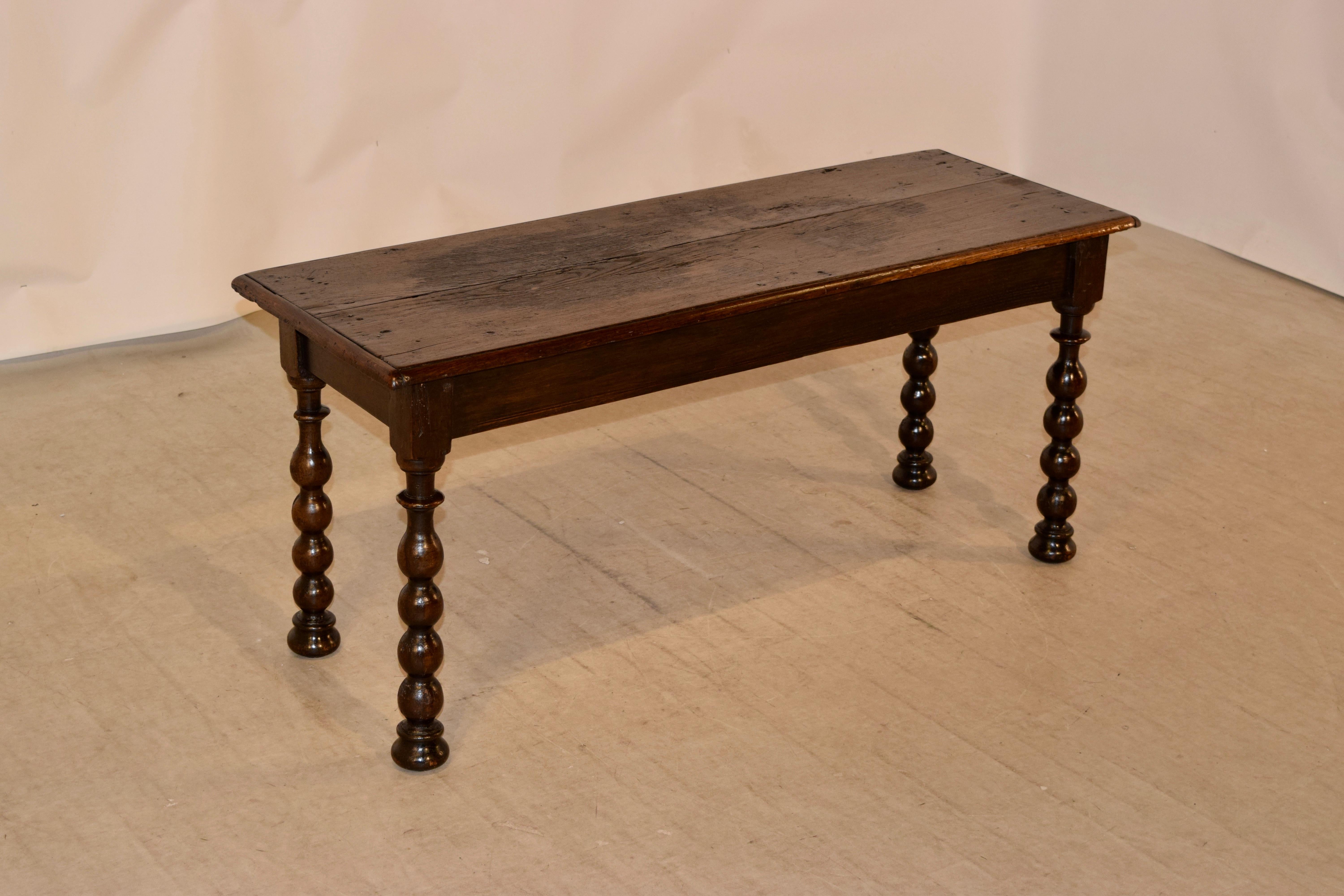 19th century oak bench from France with a beveled edge around the top following down to a simple apron and supported on hand turned bobbin legs, ending in bun feet.