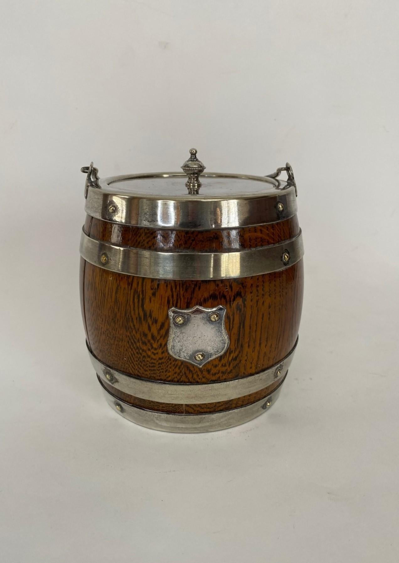 Whatever you fancy...Keep your buns warm or elegantly offer ice on your bar...

This attractive 19th century Victorian English Oak lidded biscuit barrel with a white interior ceramic liner and silver plated handle, top, shield  and bands. . A