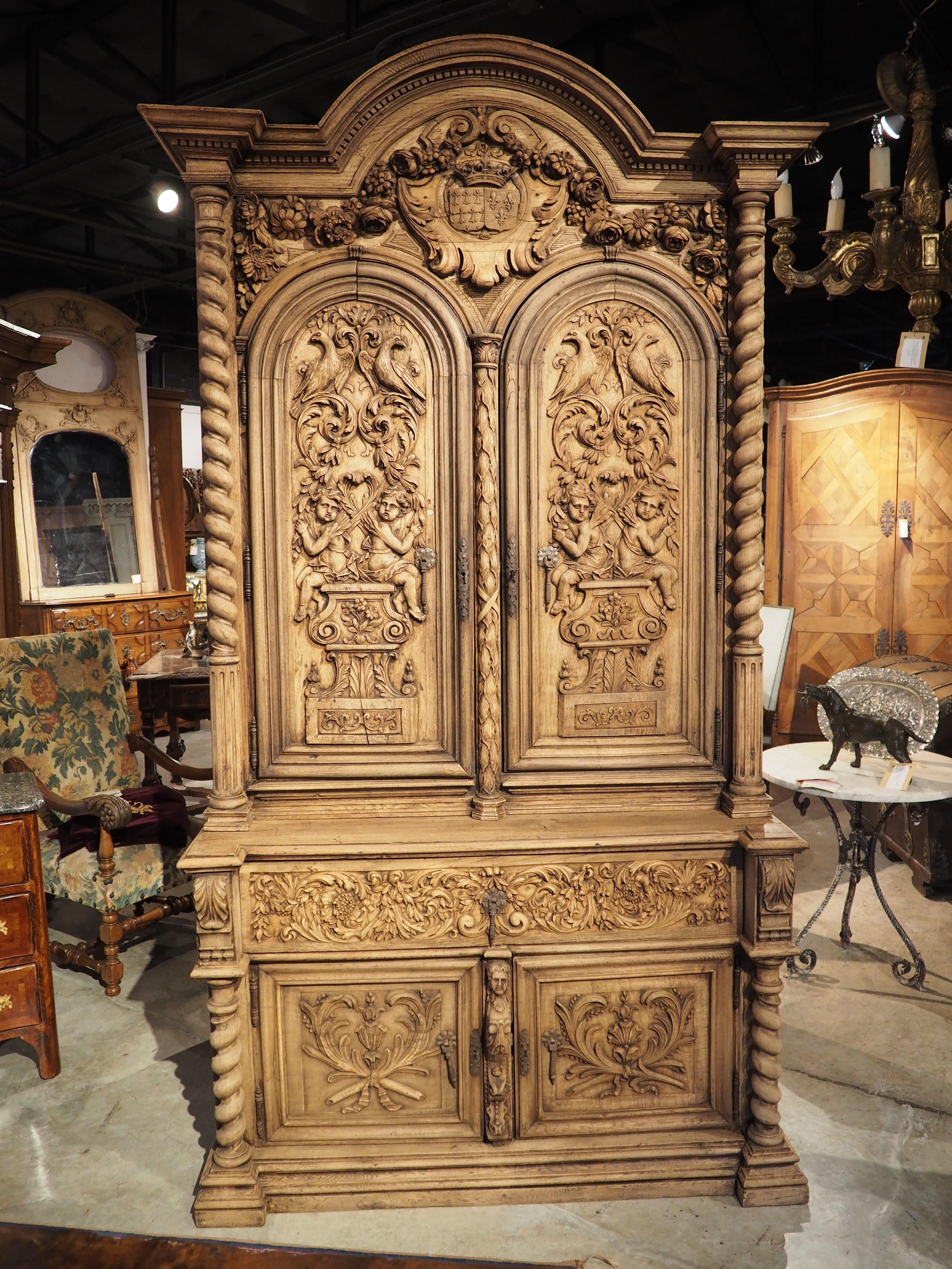 An unbelievably detailed oak buffet deux-corps that was hand-carved in France in the 1800’s, this piece features the Arms of Brittany and France. The original finish was recently stripped, giving the beautiful wood grain more prominence and
