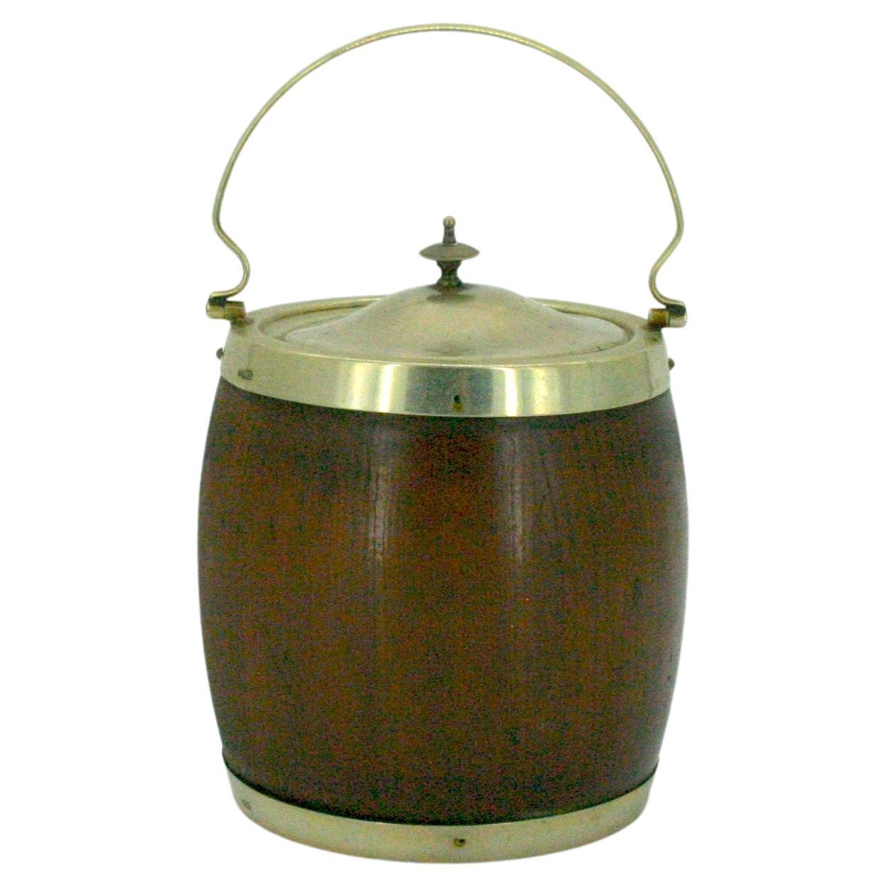 English oak with silver plated frame ice bucket / biscuit barrel with white interior ceramic liner. The biscuit box / ice bucket features a removable silver plate cover and holding top handle. It's in good antique condition with wear appropriate