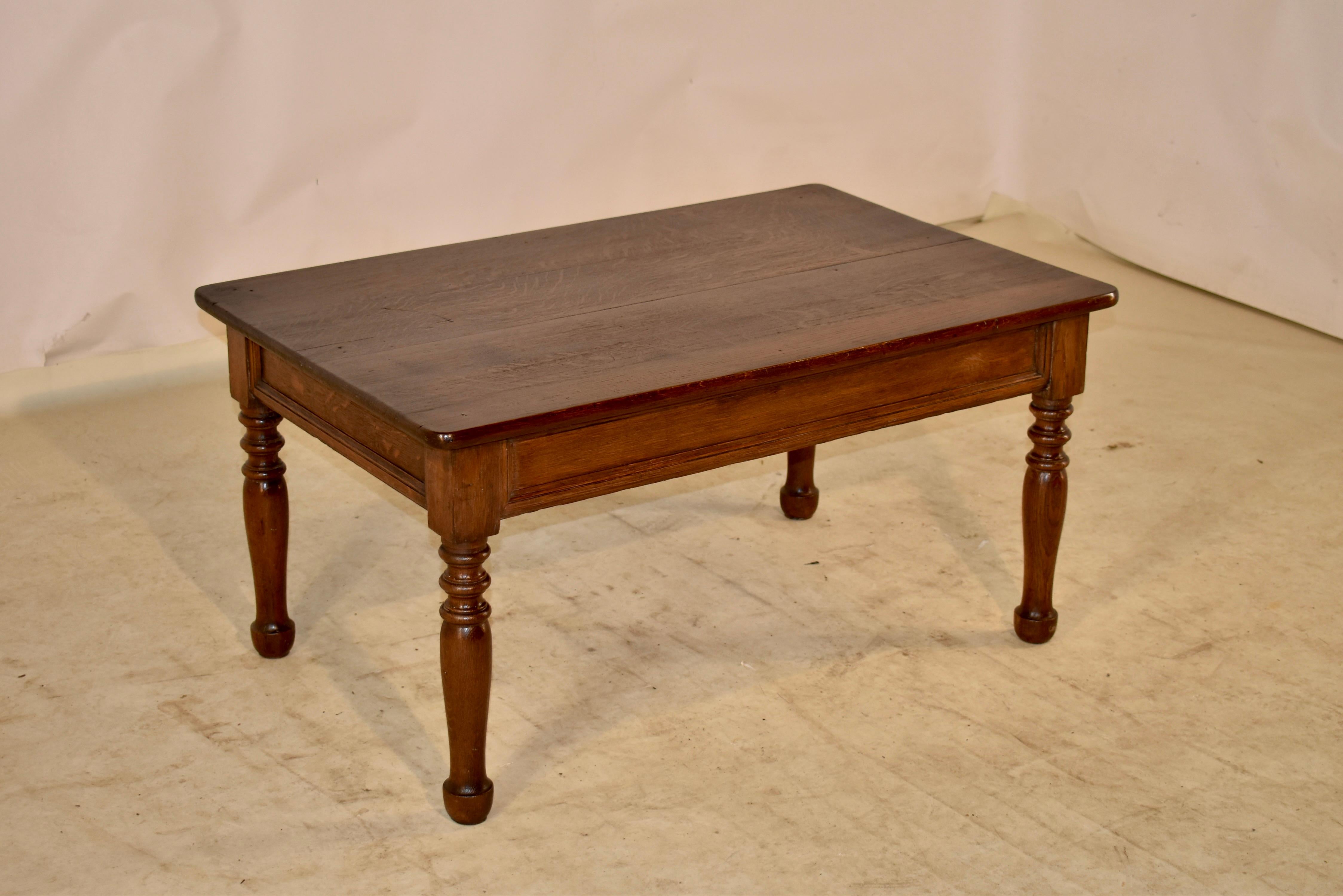 19th Century oak coffee table from England with a plank top over a simple and elegantly paneled apron. The table is supported on hand turned legs, ending in turned feet. Lovely size and color.