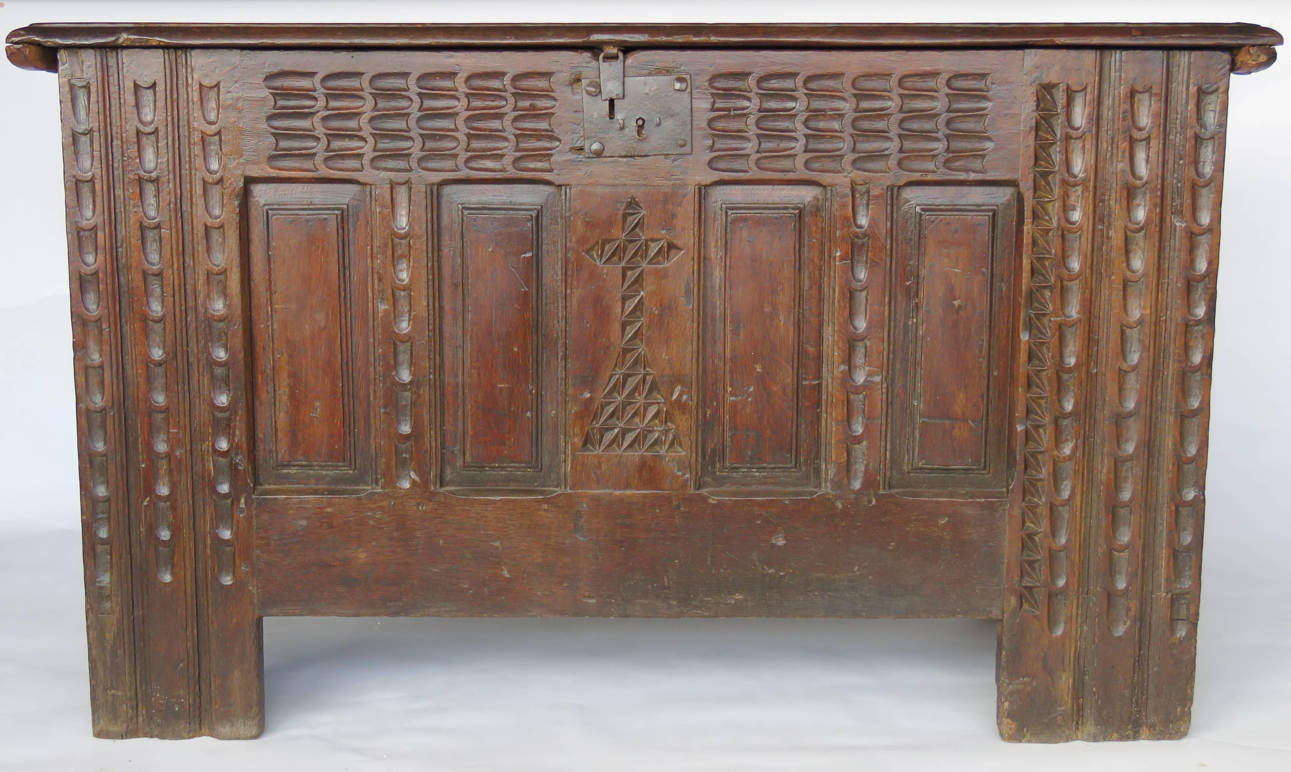 Rectangular hinged molded top over a deeply carved case decorated with central cross, surrounded with panels and chip-carved frieze, panelling on both sides, original iron shield lock and hardware.