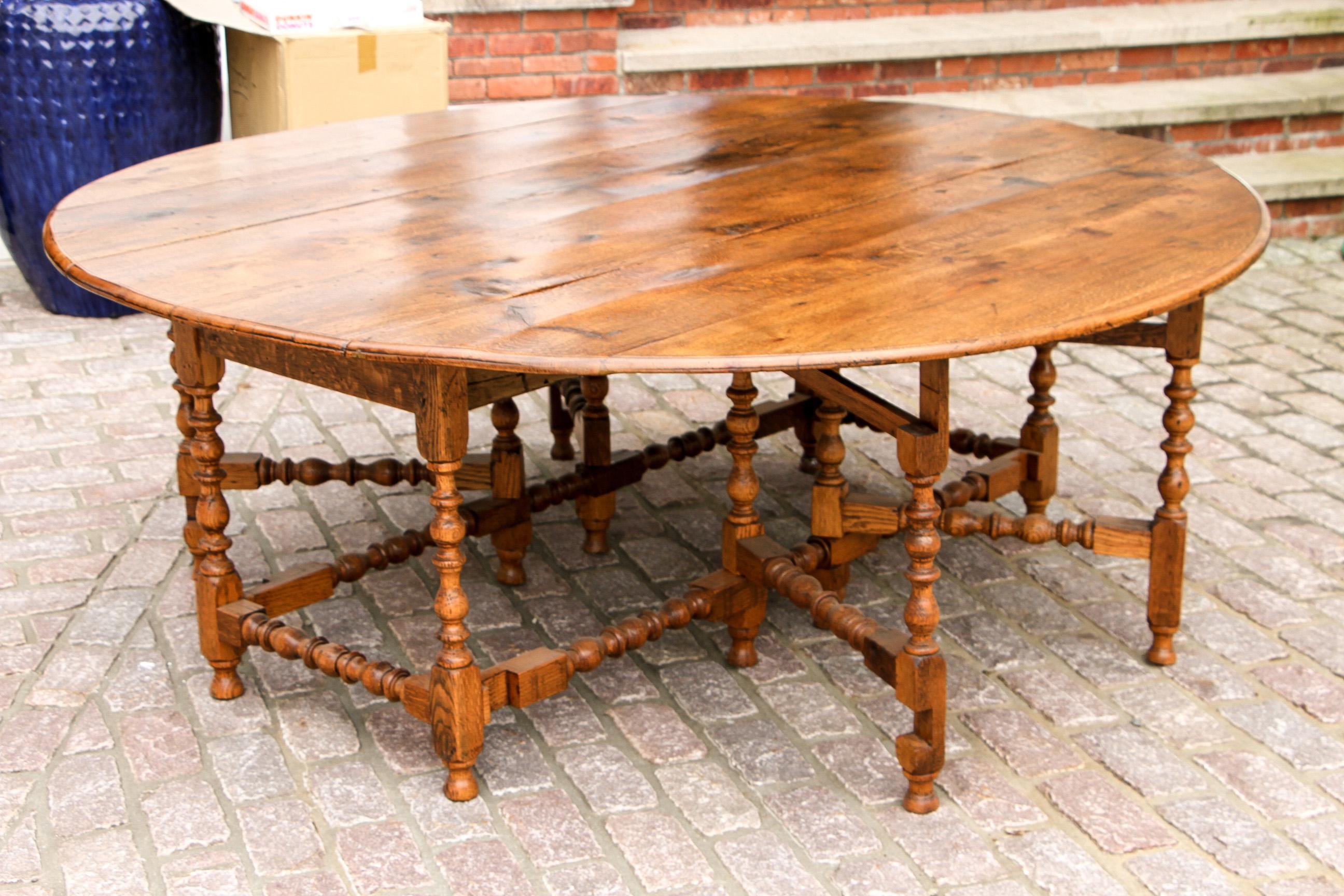 19th century oak drop-leaf gate-leg dining table, heavily turned legs, box stretcher. Expected wear and signs of use including evidence of past repairs, checking, surface scratching and sporadic nicking, some warping to areas. Measures: 79 1/2