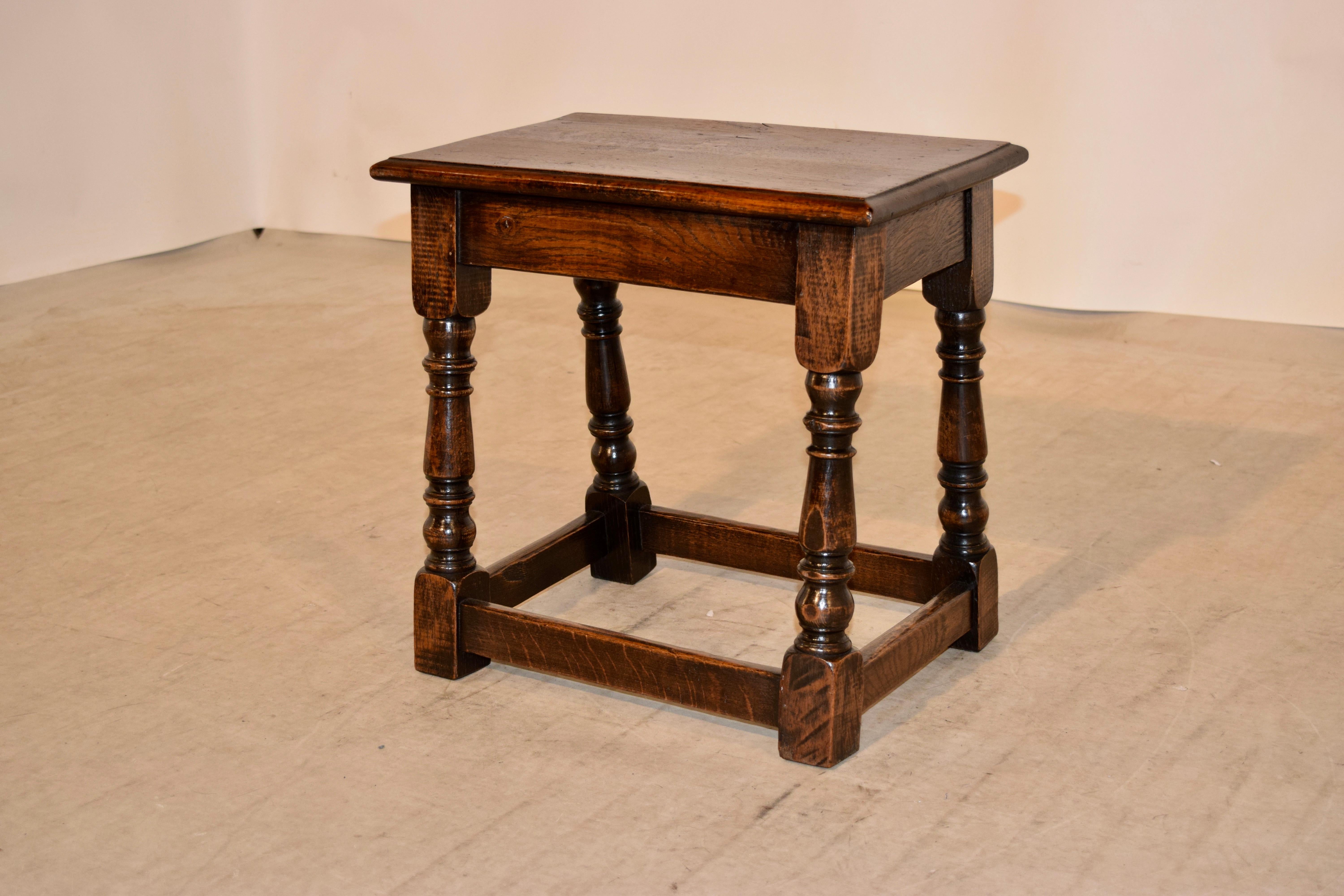 19th century oak joint stool from England with a bevelled edge around the top following down to a simple apron and hand turned splayed legs, joined by stretchers. Pegged construction.