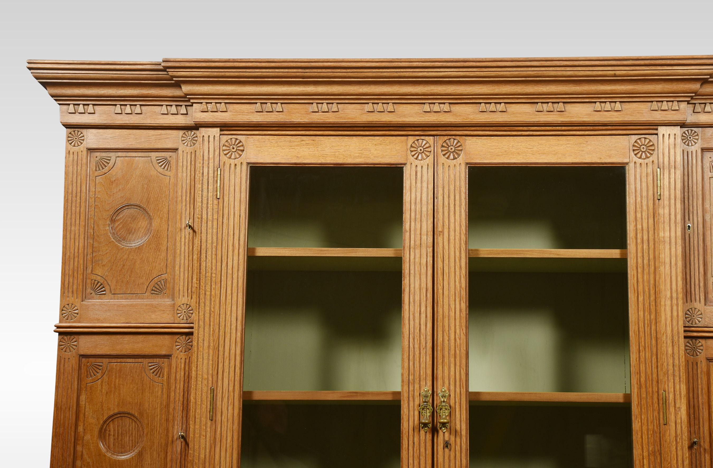 19th-century oak kitchen cupboard, the carved moulded cornice above two large glazed doors opening to reveal an adjustable shelved interior having two drawers below. Flanked by three panelled doors with circular carved detail. The base section is