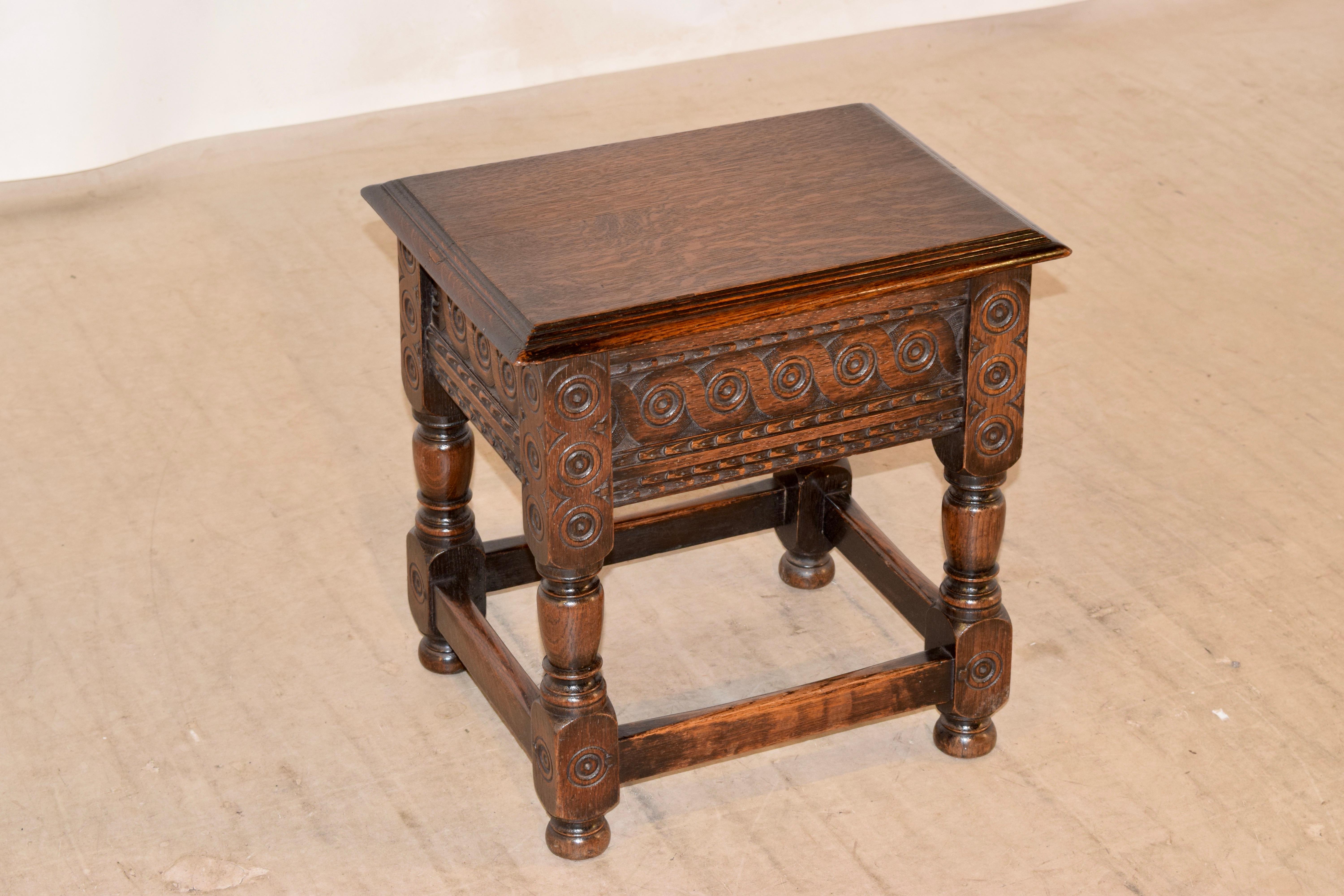 19th century oak lift-top stool from England with a beveled edge around the top, which lifts to reveal storage. The base is wonderfully hand carved and is supported on hand turned legs, joined by simple stretchers and raised on turned feet.