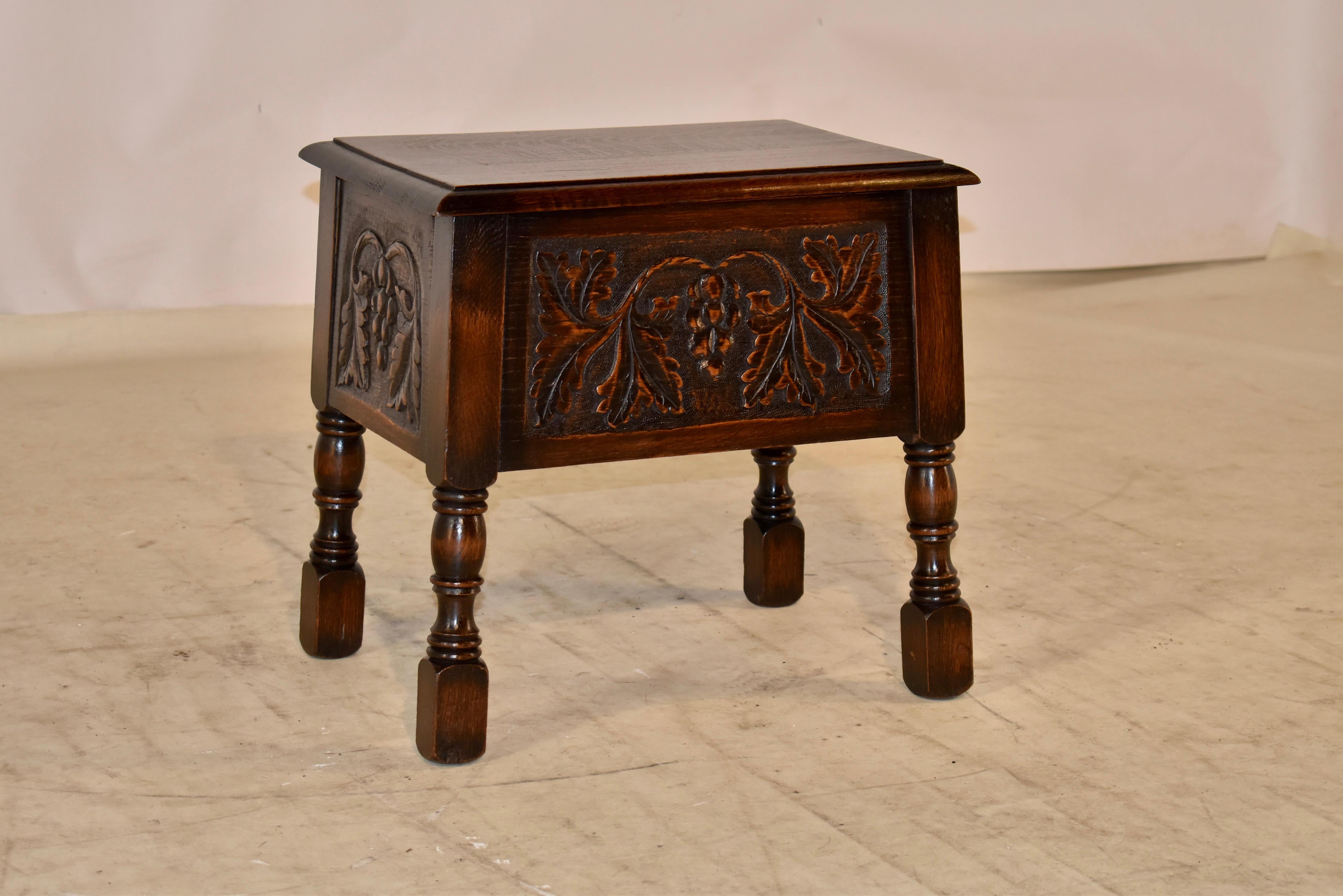 19th century oak lift top stool from England. The top has a beveled edge and lifts to reveal storage. The stool is hand carved decorated on all four sides for easy placement in any space, and is supported on hand turned legs. the hand carved