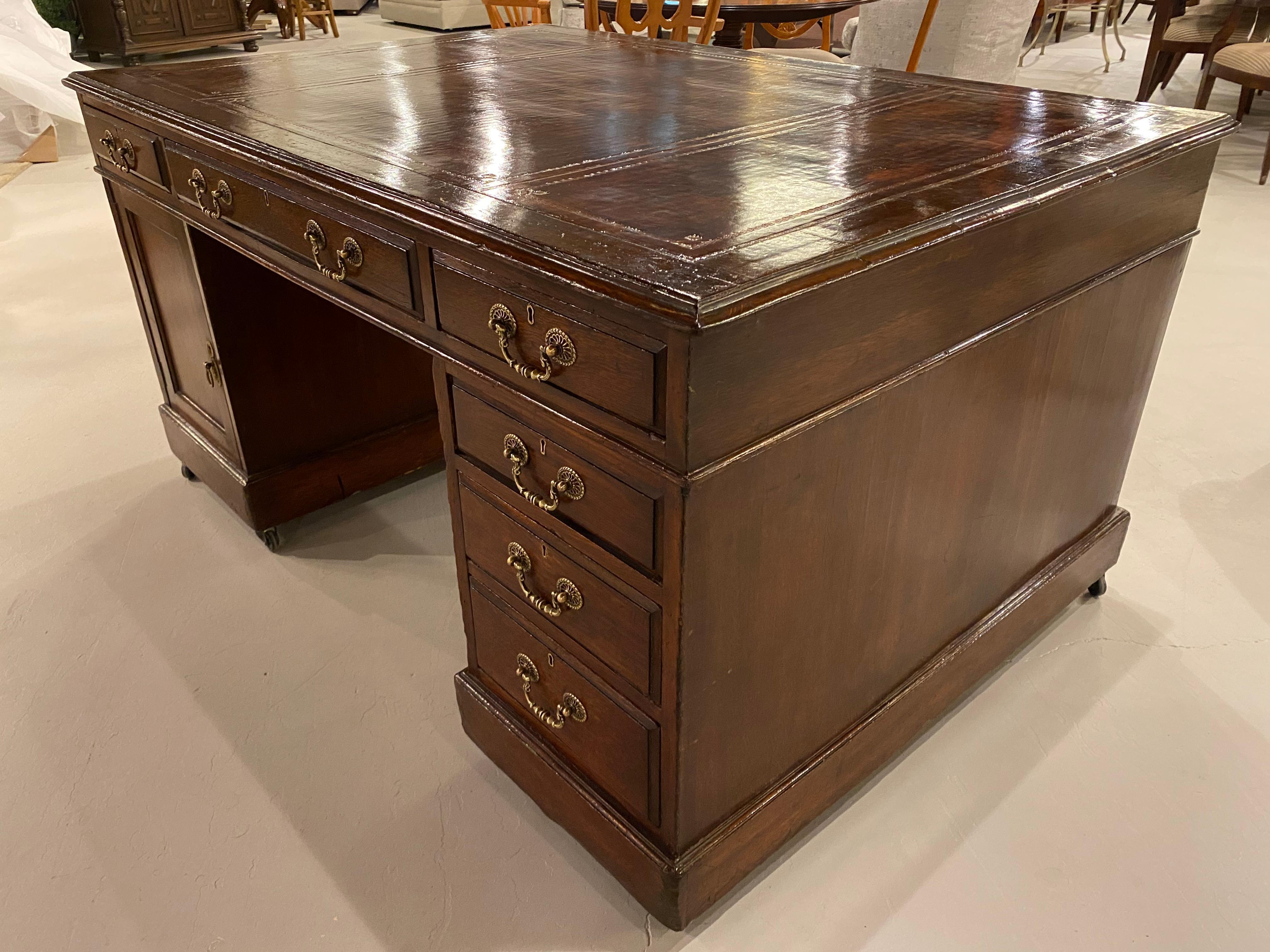 A wonderful probably, 19th century oak partners desk, with a leather writing surface. Each side has a bank of drawers and a cupboard door for serious storage, or you can put both banks of drawers on the same side. The leather top has a lovely worn