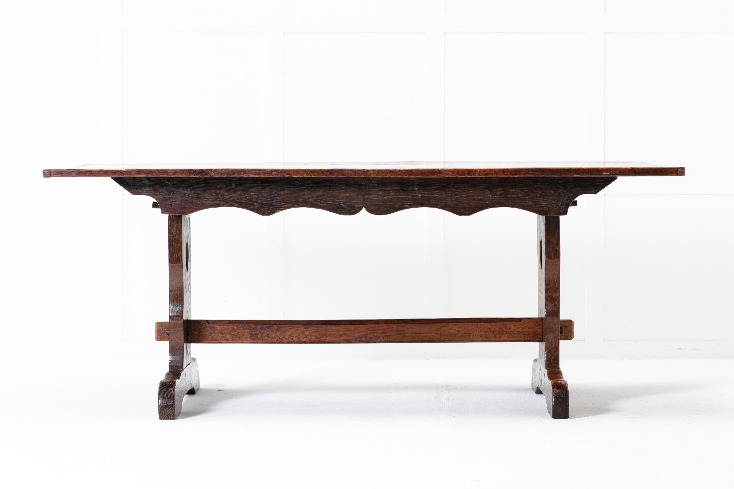 19th Century refectory table with its pegged top consisting of three solid planks of oak with cleated ends. Below is a wavy carved apron on both sides. The end supports have carved out shapes of hearts and keyed-through tenon joints connecting the