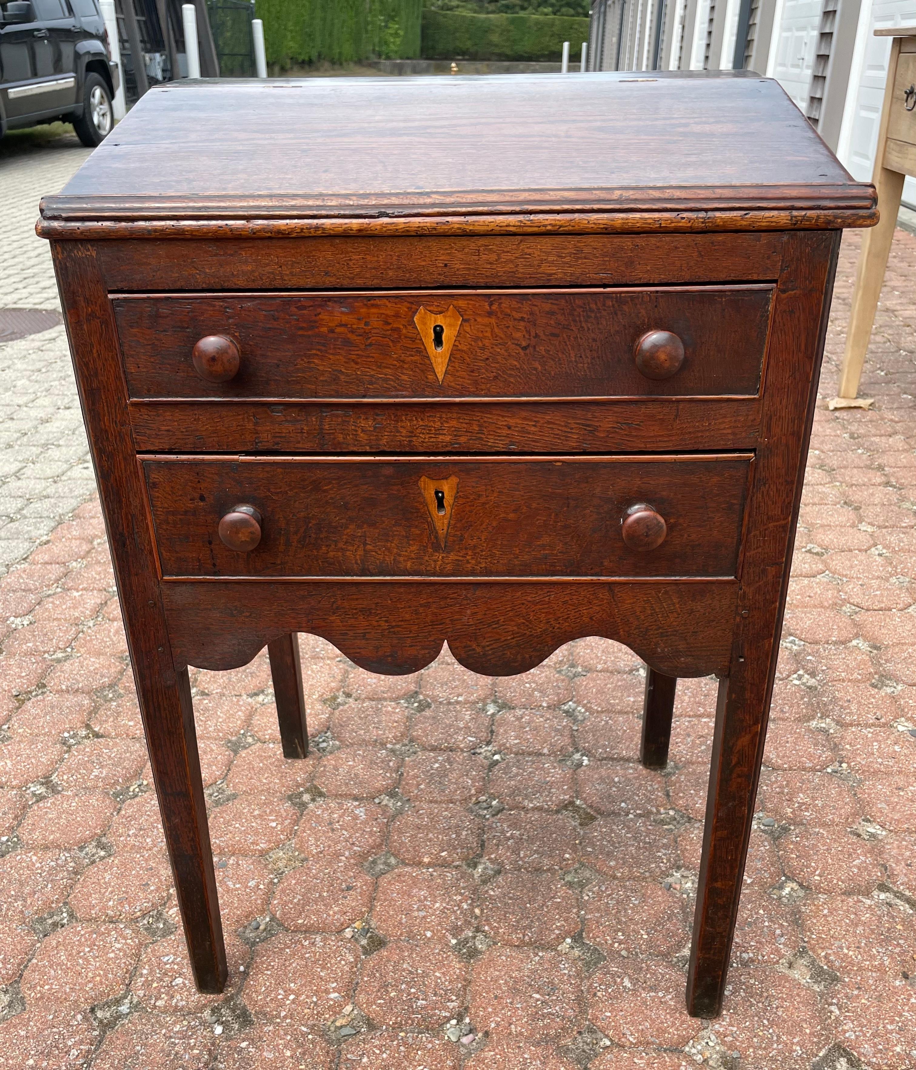 19th century oak school desk or lectern.  Lift top reveals document compartment, over two lower drawers each with inlaid fruitwood key escutcheon (no key).  Nicely shaped skirt at sides and front, on gently tapered legs.