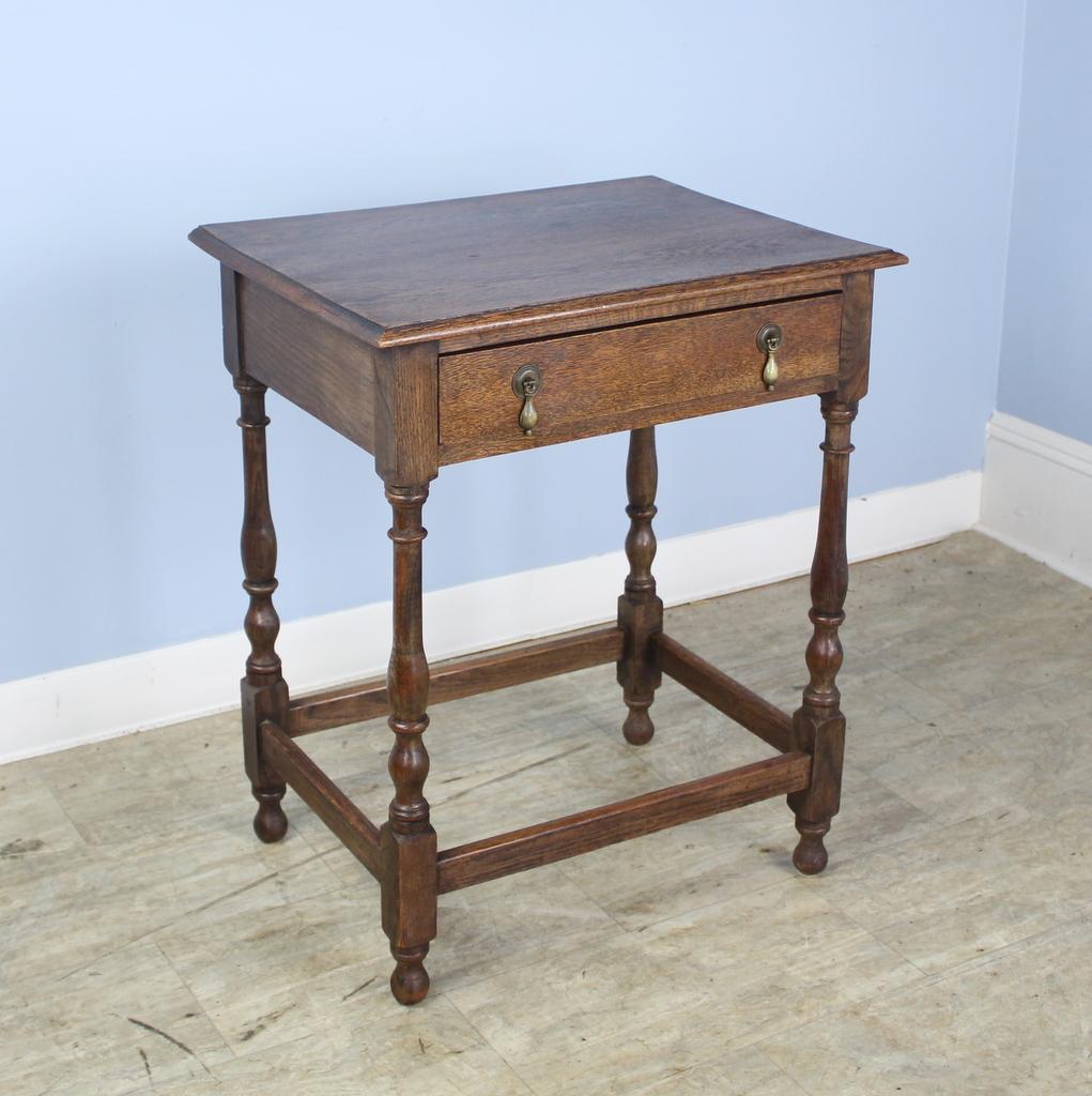 An elegant oak side table with a pretty top, quite free of distress, nicely turned legs, and original brass tear drop escutcheons.