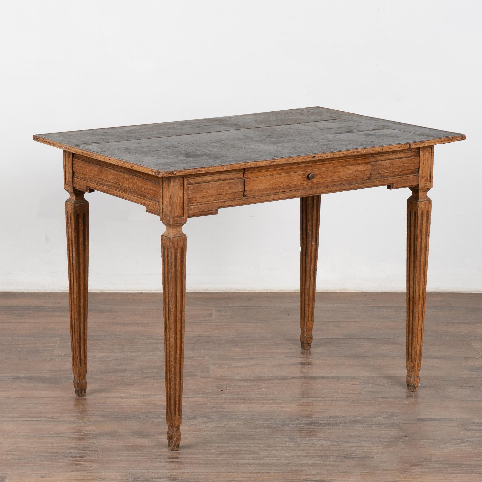 Table d'appoint en chêne suédois avec pieds cannelés et un seul tiroir. Remarquez la partie supérieure recouverte d'un papier rappelant un motif Louis Vuitton.
Bien que cette table d'appoint révèle des années d'utilisation avec des rayures, des
