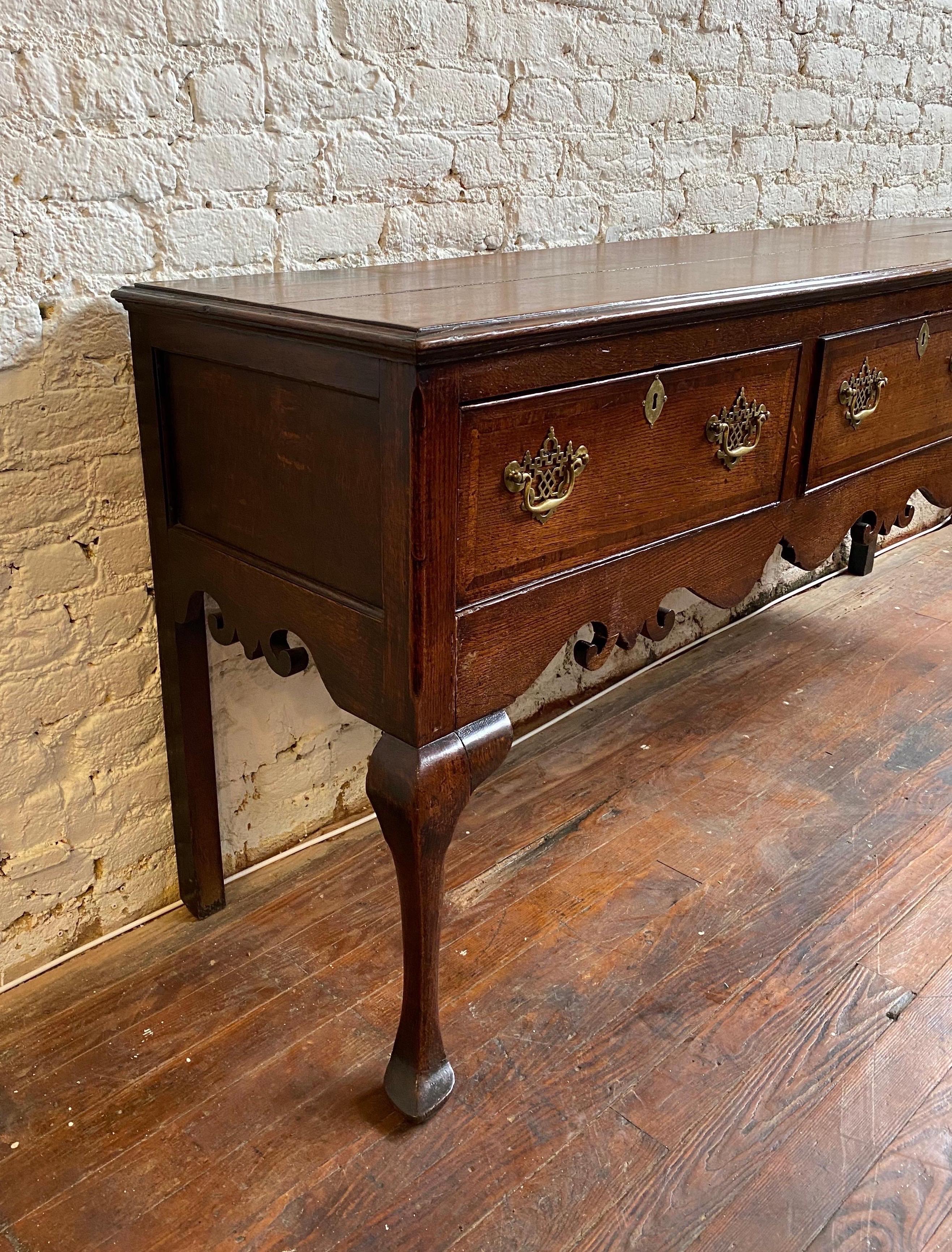 19th century oak welsh dresser base- two board top over three crossbanded drawers, a carved apron, cabriole legs and slipper feet. Great color and patina.