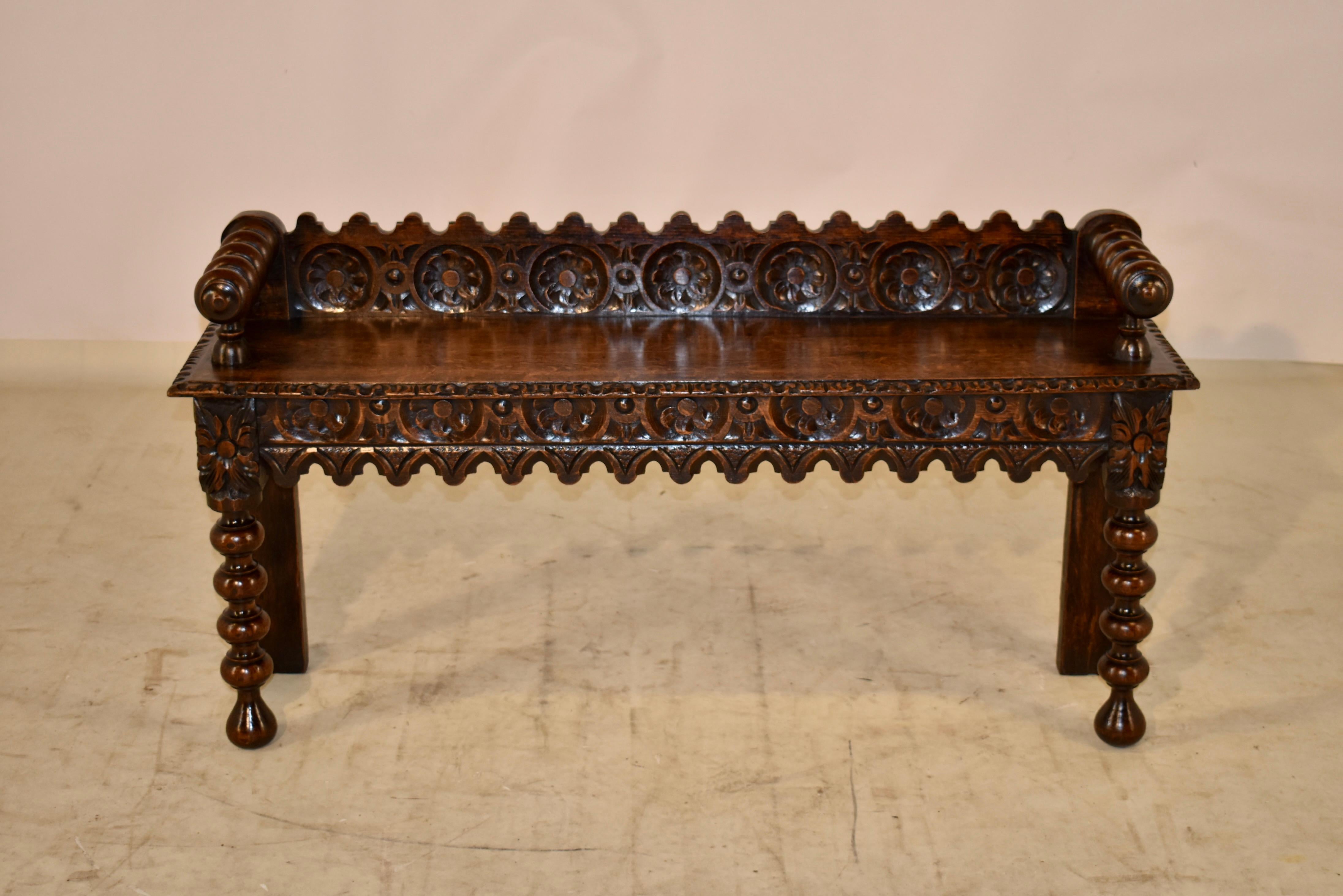 19th Century English oak carved window seat with a lovely hand-carved and scalloped back, following down to hand turned arms, which are resting upon the seat. the arm height is 24.5 inches. The seat has a hand carved and beveled edge over a gorgeous