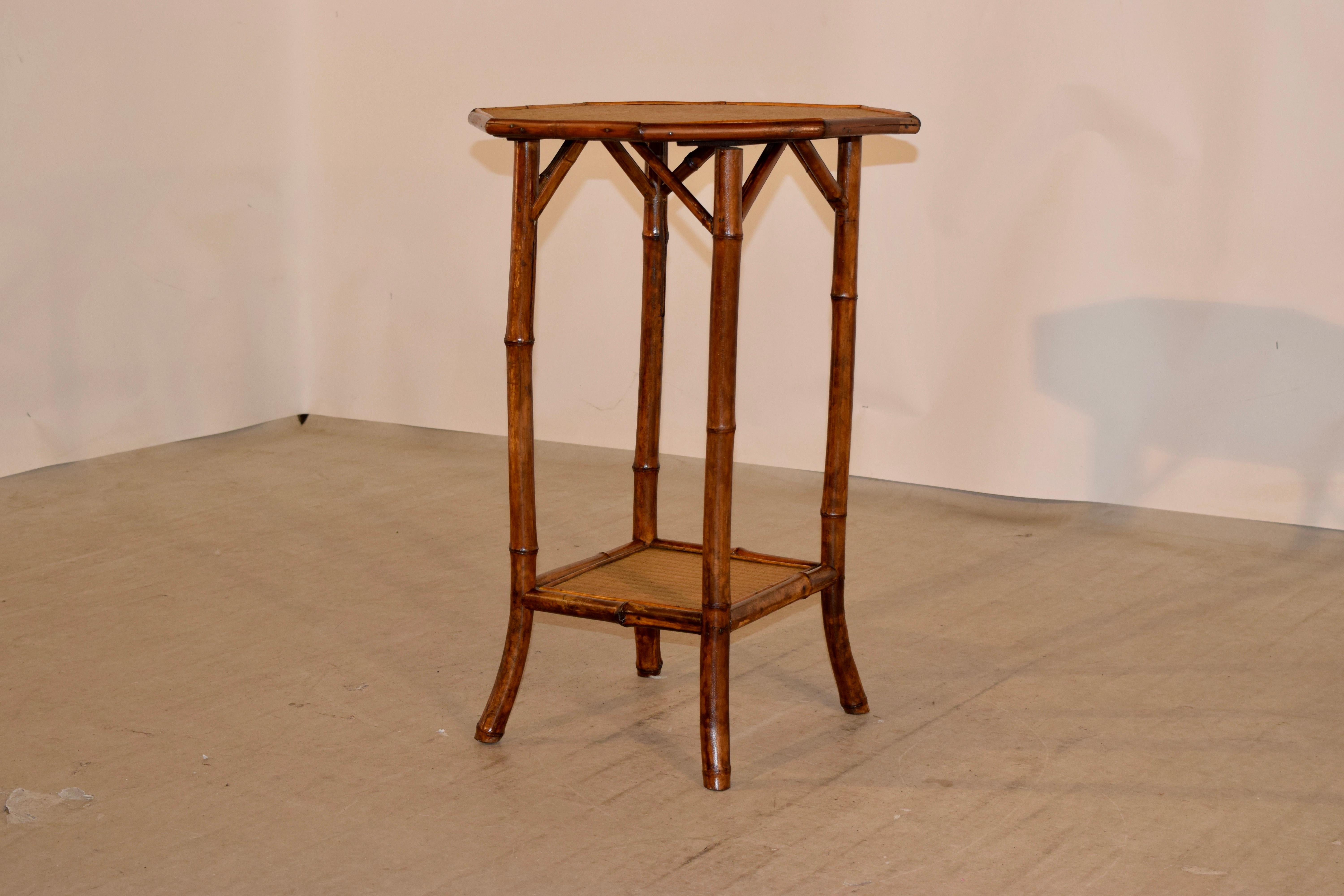 19th century bamboo table from France with an octagonal shaped top and splayed legs, which are joined by a single lower shelf. The top and lower shelf are covered in rush.