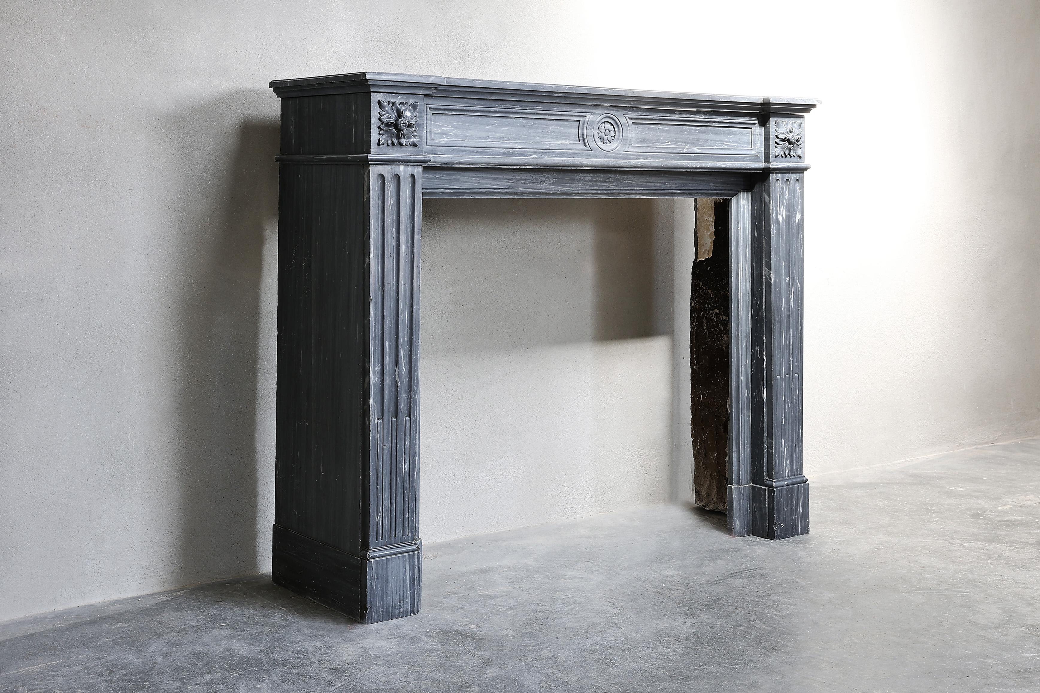 Beautiful antique fireplace of Blue Turquin marble from the 19th century! This fireplace is in the style of Louis XVI, has straight shapes and also elegant ornaments in the front part and on the legs. An antique fireplace that fits perfectly within