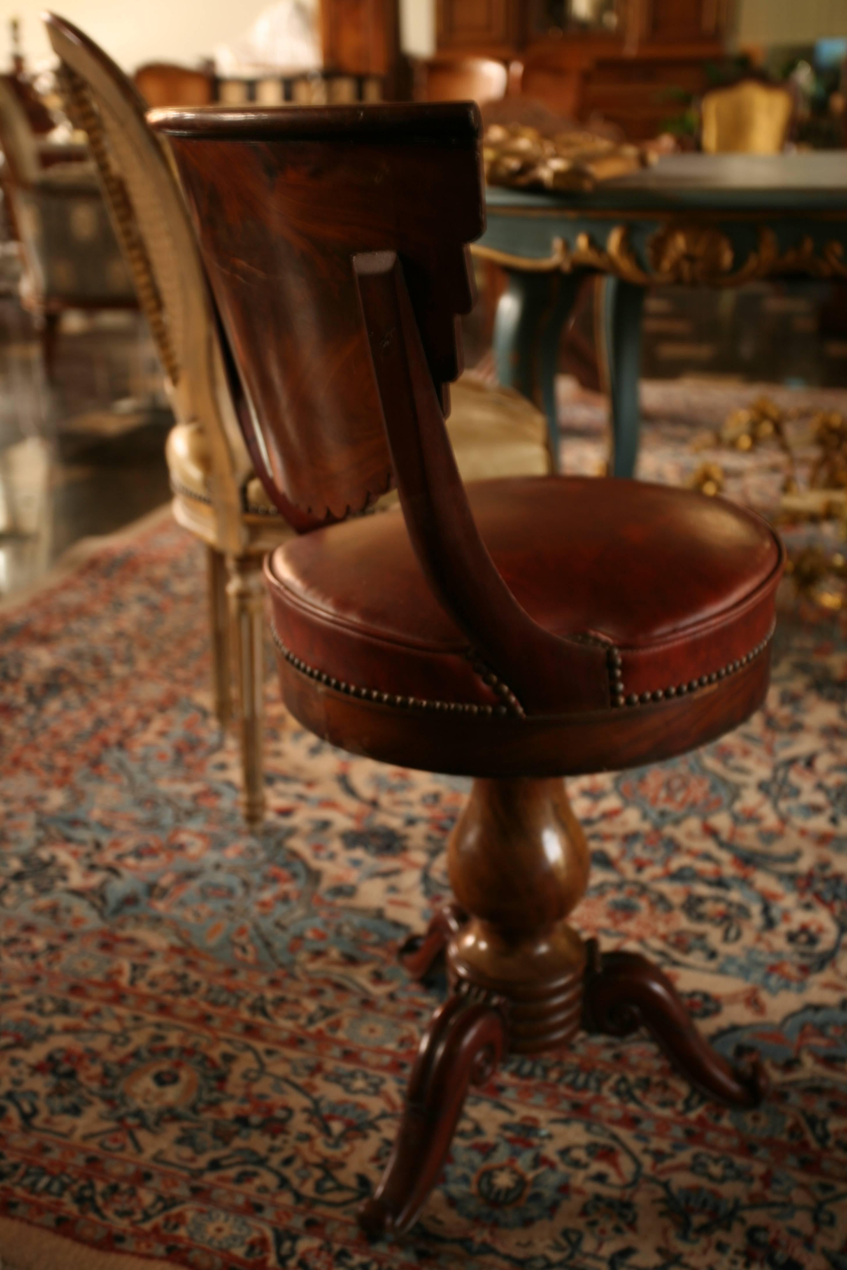 Desk chair of the Restoration Period with rotating circular seating in red leather, mahogany and mahogany veneer and blackened wood net, baluster shaft ended with a tripod base.
England, 1880.

   