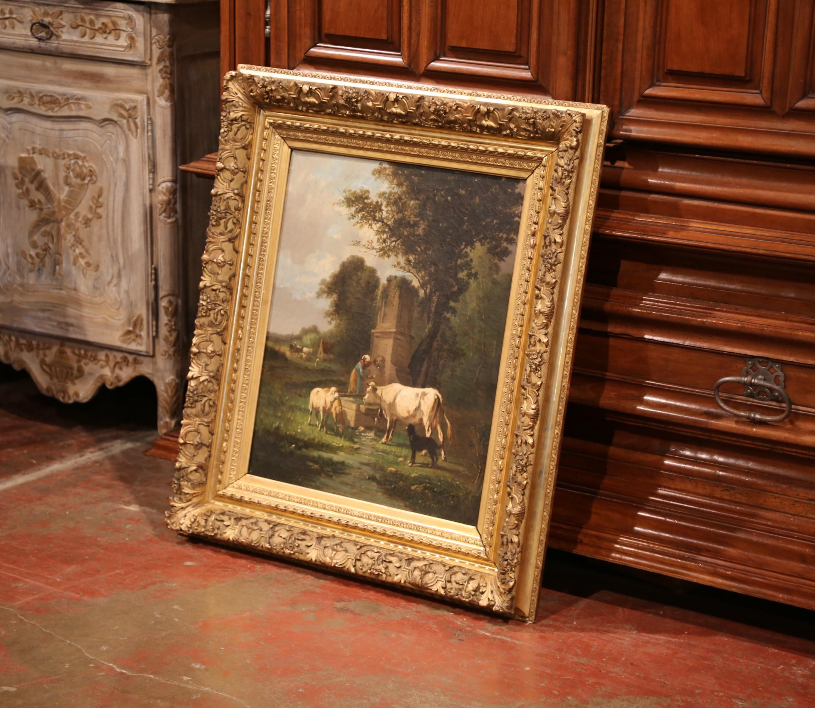 This exquisite oil on canvas pastoral painting was created in Spain circa 1860; set inside the original carved gilt frame, the painting depicts a pastoral scene featuring a farmer getting water from a stone fountain with sheep, cows and dog