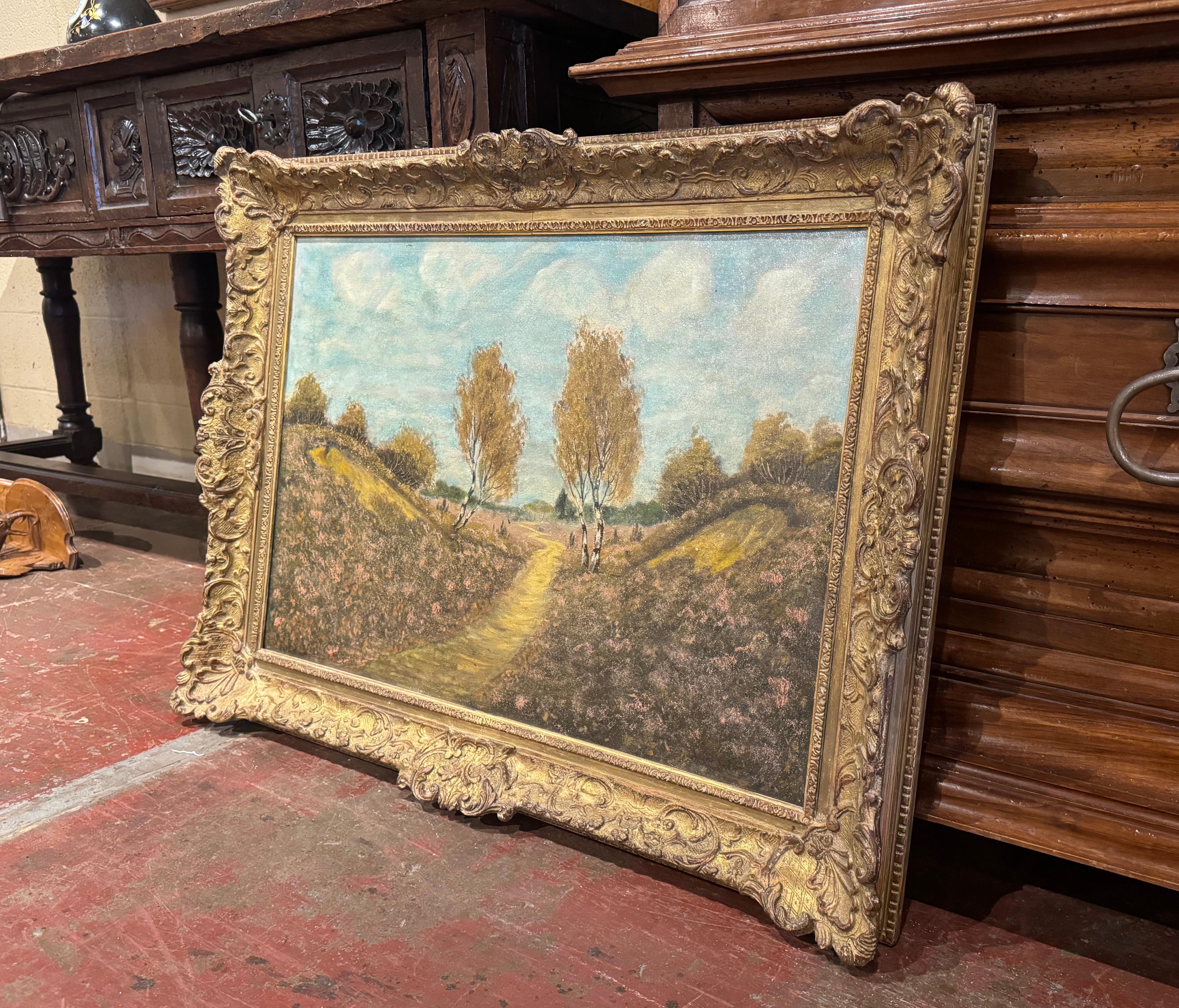 Decora un estudio o una guarida con este hermoso cuadro antiguo de paisaje. Pintado a mano en Bélgica hacia 1890, y colocado en el marco original de madera dorada tallada, este gran cuadro representa un sereno paisaje natural con un camino