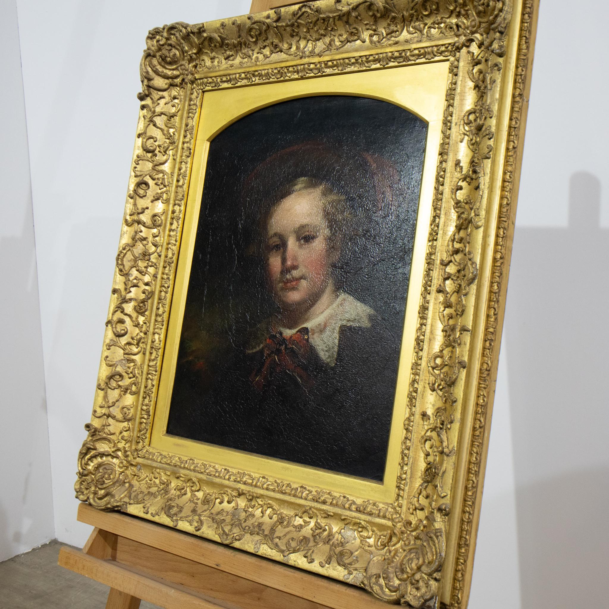 An attractive 19th century painting of a young boy in a feathered hat with a white collar, this is unsigned oil on board and in an original ornately decorated gilt frame. With tones of dark red and brown, this is a great piece for a country home or
