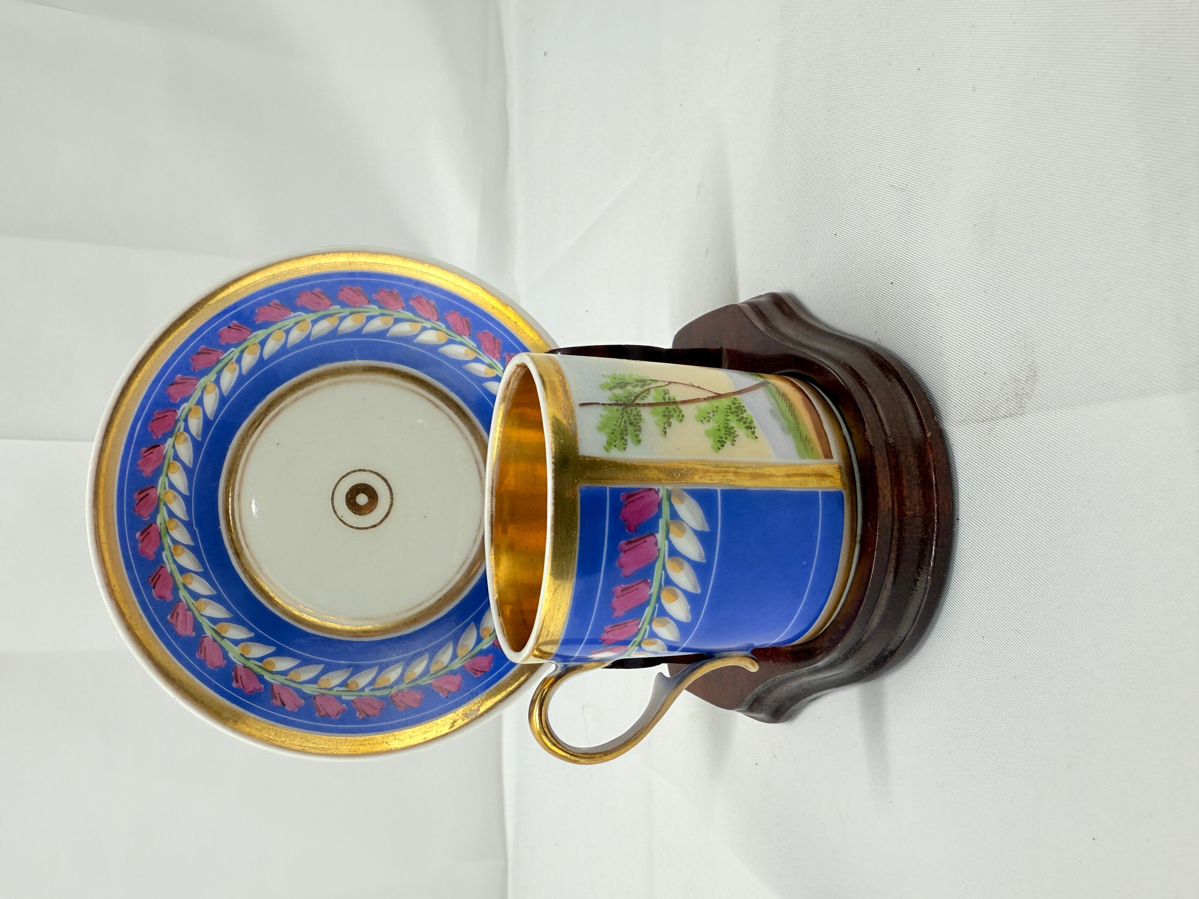 Dieses exquisite neoklassizistische Tassen- und Untertassenset aus dem 19. Jahrhundert ist der Inbegriff feiner französischer Porzellankunst und spiegelt die Eleganz und Anmut einer Epoche wider, die das klassische Altertum verehrte. Das mit großer