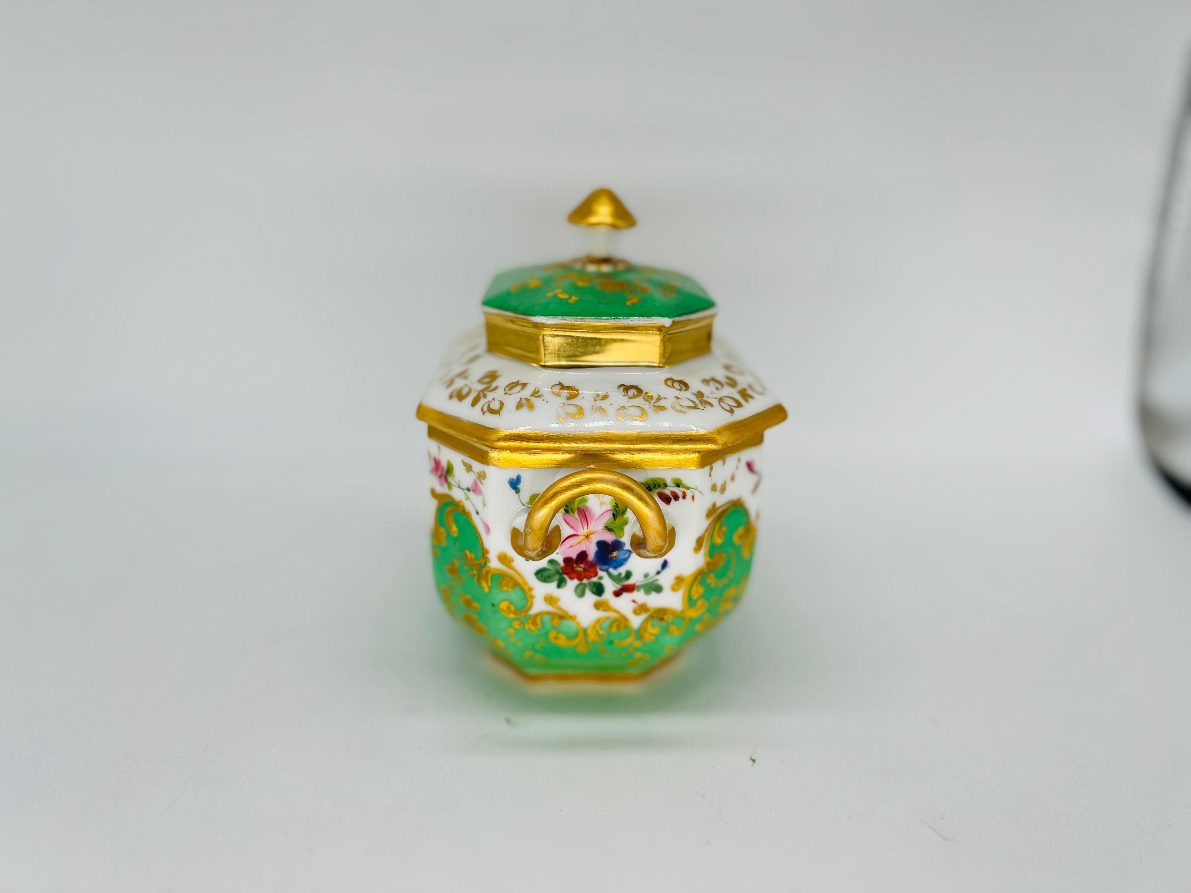 Este elegante azucarero cubierto de porcelana Old Paris del siglo XIX ejemplifica la refinada artesanía y la lujosa estética de la época. El azucarero está ricamente adornado con motivos florales de esmalte pintados a mano, con delicadas flores en