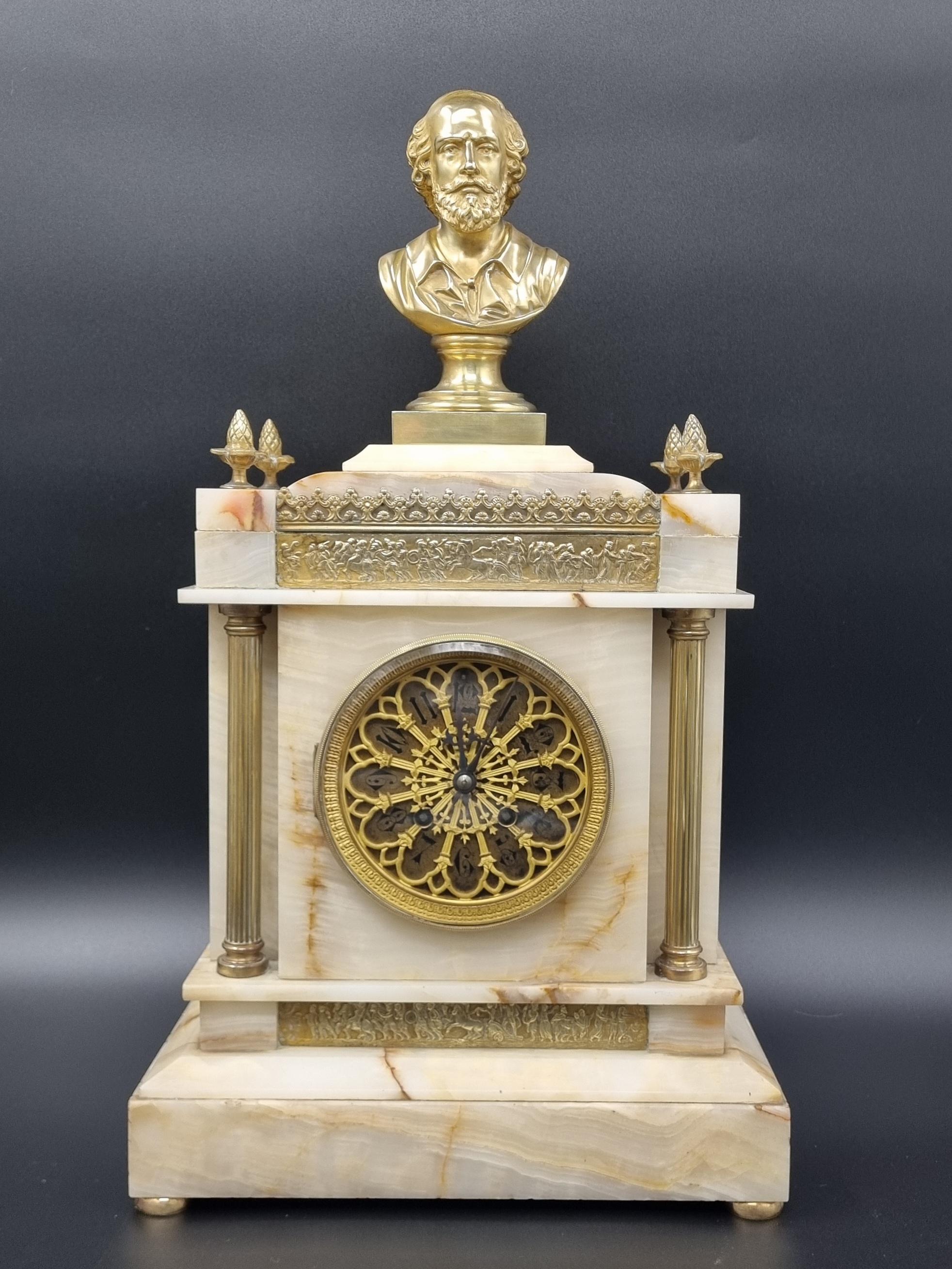 A William Shakespeare Gothic revival mantle clock, dating back to the mid-19th century, superb quality and is made from onyx and gilt bronze. The clock showcases reeded column supports and classical friezes adorned with exquisitely detailed scenes