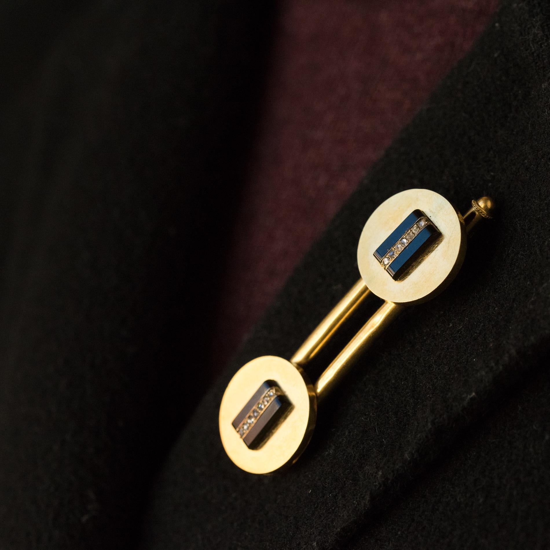 Set in 18 karats yellow gold, eagle's head hallmark.
Composed of a pair of vest buttons and a brooch, this antique jewel of clothing is composed of round-shaped motifs in satin gold set with a bar of onyx each supporting a line of 7 rose- cut