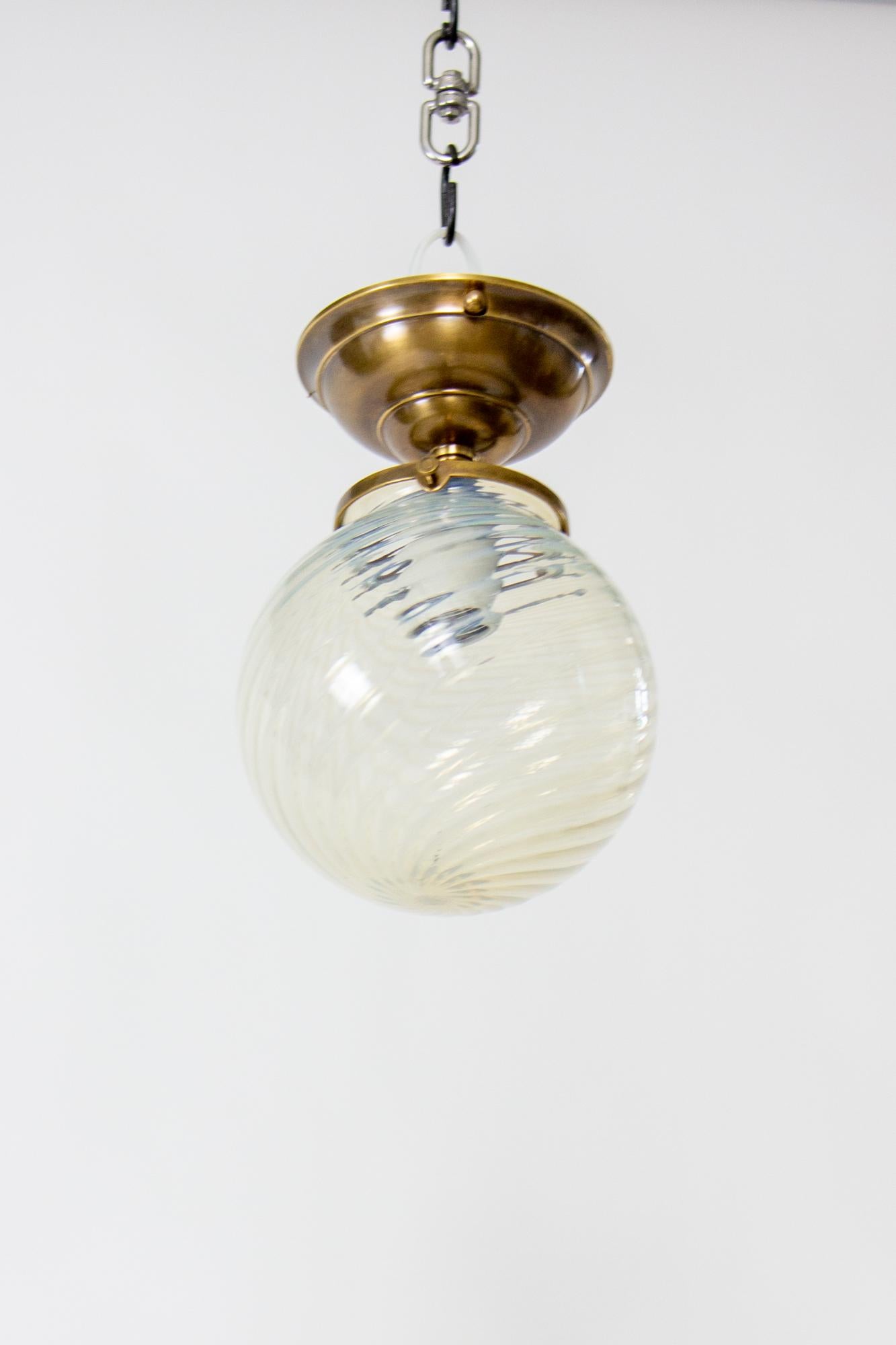 Opalescent globe flush mount light fixture. Glass is late 19th Century blown glass, carrying evidence of the original glass blowing process in the tip of the swirl pattern. The glass is clear and opal, and in some light takes on a blueish tone. It