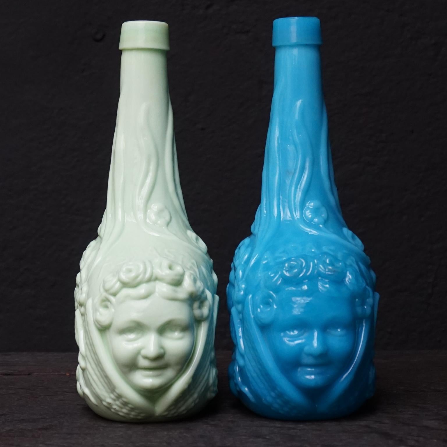 Stunning set of 19th century Victorian figural Aspasia liquor bottles in pressed opaline milk glass.

One in a vivid almost turquoise bright blue and one in a light sage/pistachio green colour. 
Richly adorned with a cherub type face to each end