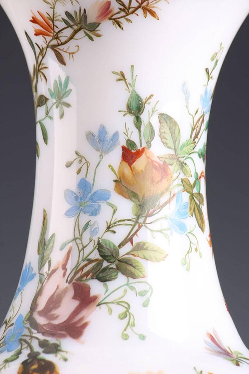 Sizeable baluster-shaped vase in white enameled Opaline, decorated with polychromatic flowers. The flowers are pulled together into bouquets that wind around the vase, a pattern that was in vogue from the 1815-1820. The rim and the base are