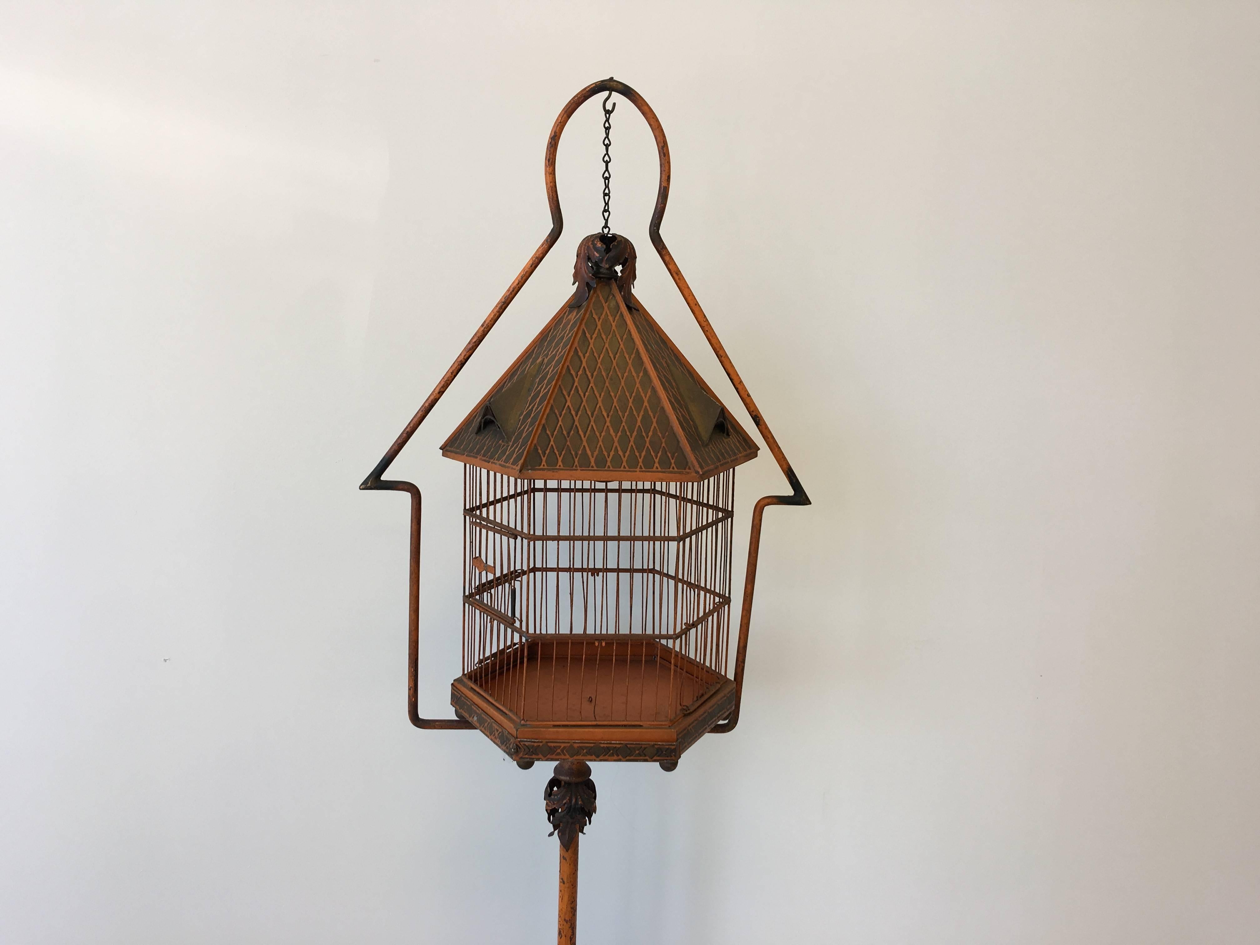 Offered is an exquisite, late 19th century tole orange and green painted birdcage and stand by P.N.F. Made in Czechoslovakia. Features shades of orange, green, and black. Three small windows along the roof with heavy fretwork along the base, and