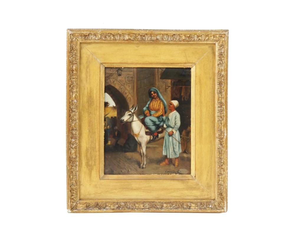 An Orientalist school 19th century painting depicting a street scene in Cairo with a man and a young woman riding a white donkey. Signed lower right: T. Merlin. Housed in an antique gilt wooden frame. On the back, there is an attached label,