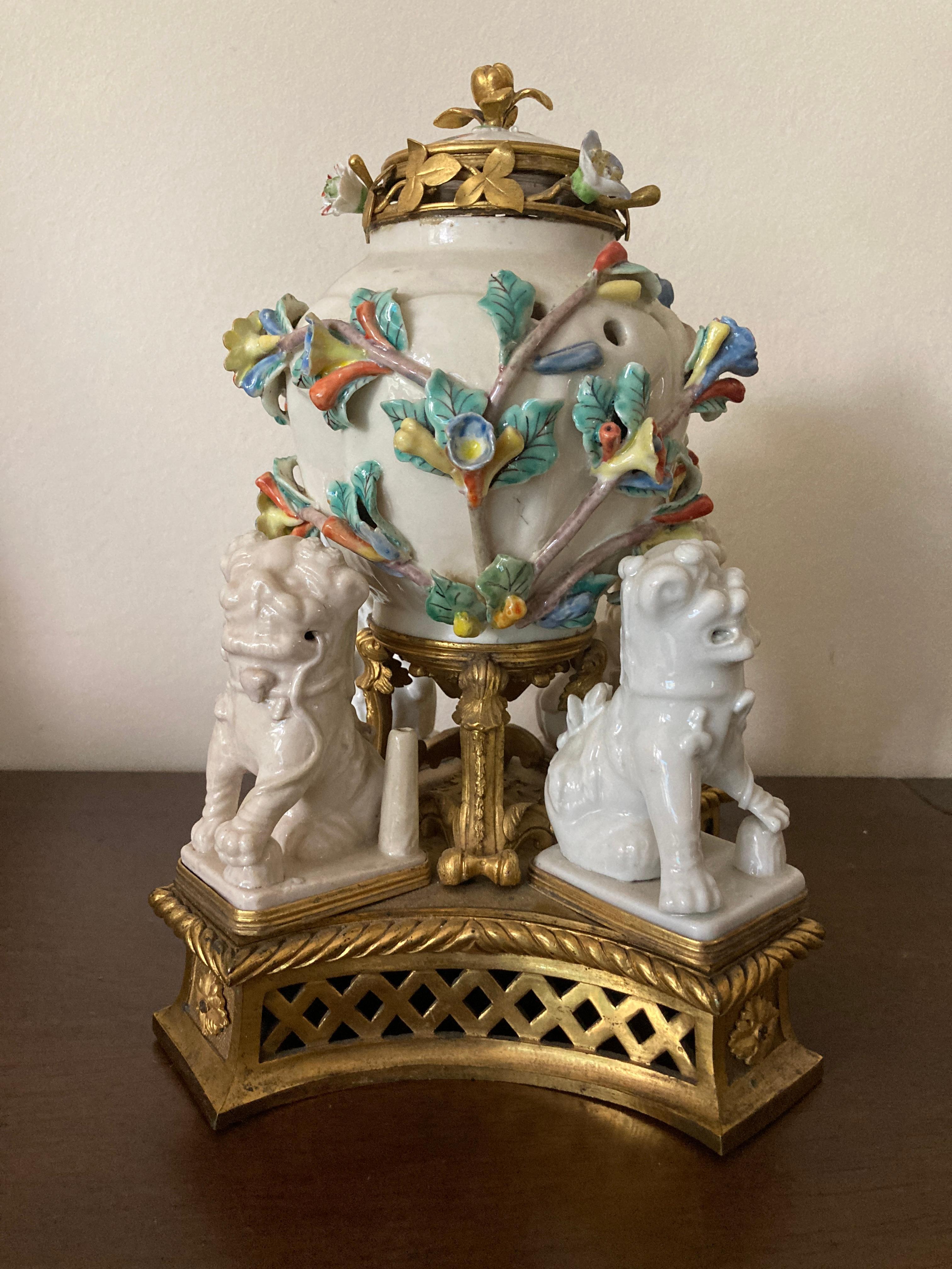 Centre de table de style oriental du XIXe siècle, de forme tripartite, comprenant un pot ovoïde en porcelaine et son couvercle avec des fleurs en suspension et trois saillies, chacune avec un lion bouddhiste couché en blanc de chine, la base en