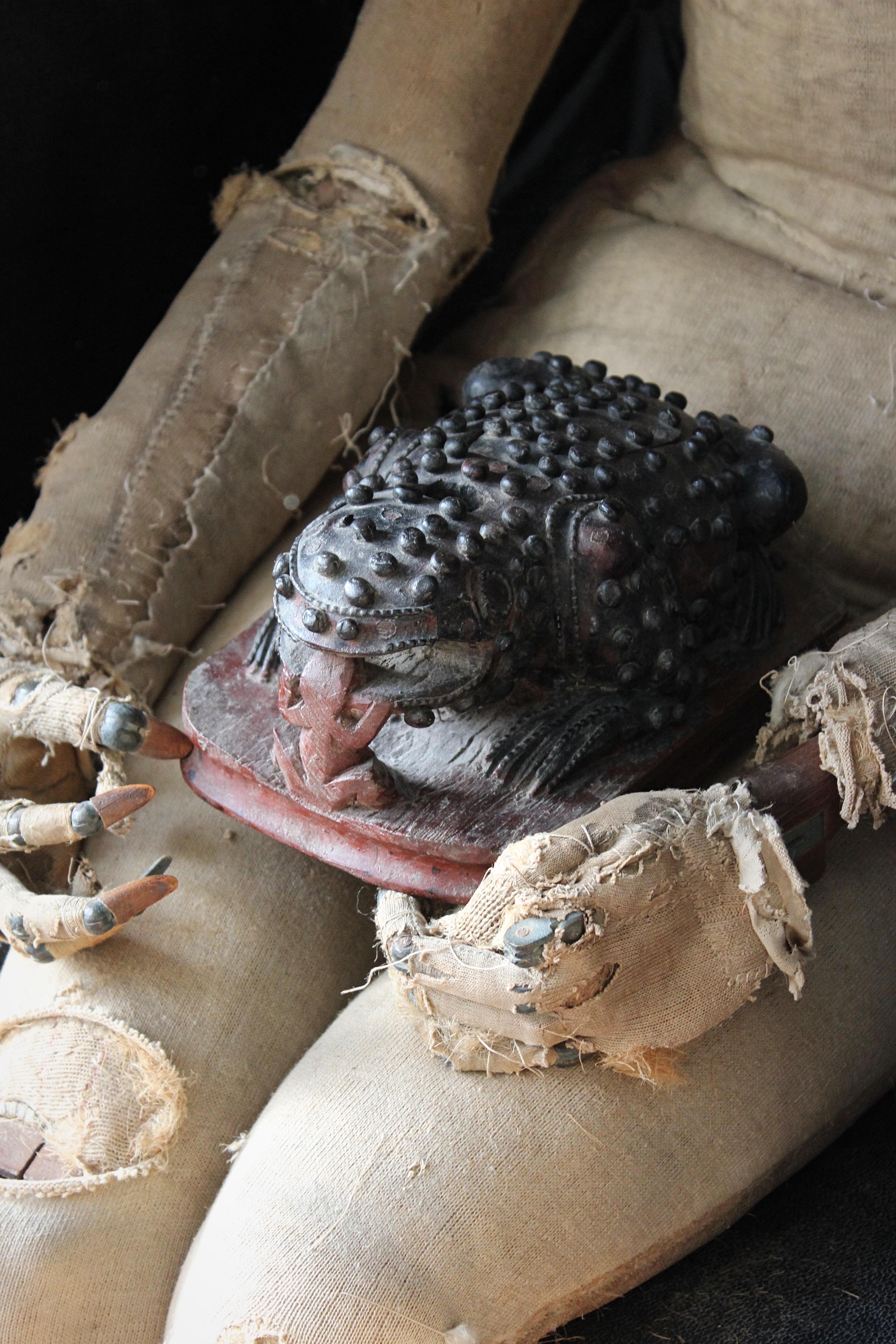 An unusual 19th century oriental wooden toad.

The carved amphibian crouching on a red wooden base, its body encrusted with warts the odd one is missing , a small red carved amphibian at its mouth.

The toad has a cavity in its back with sliding