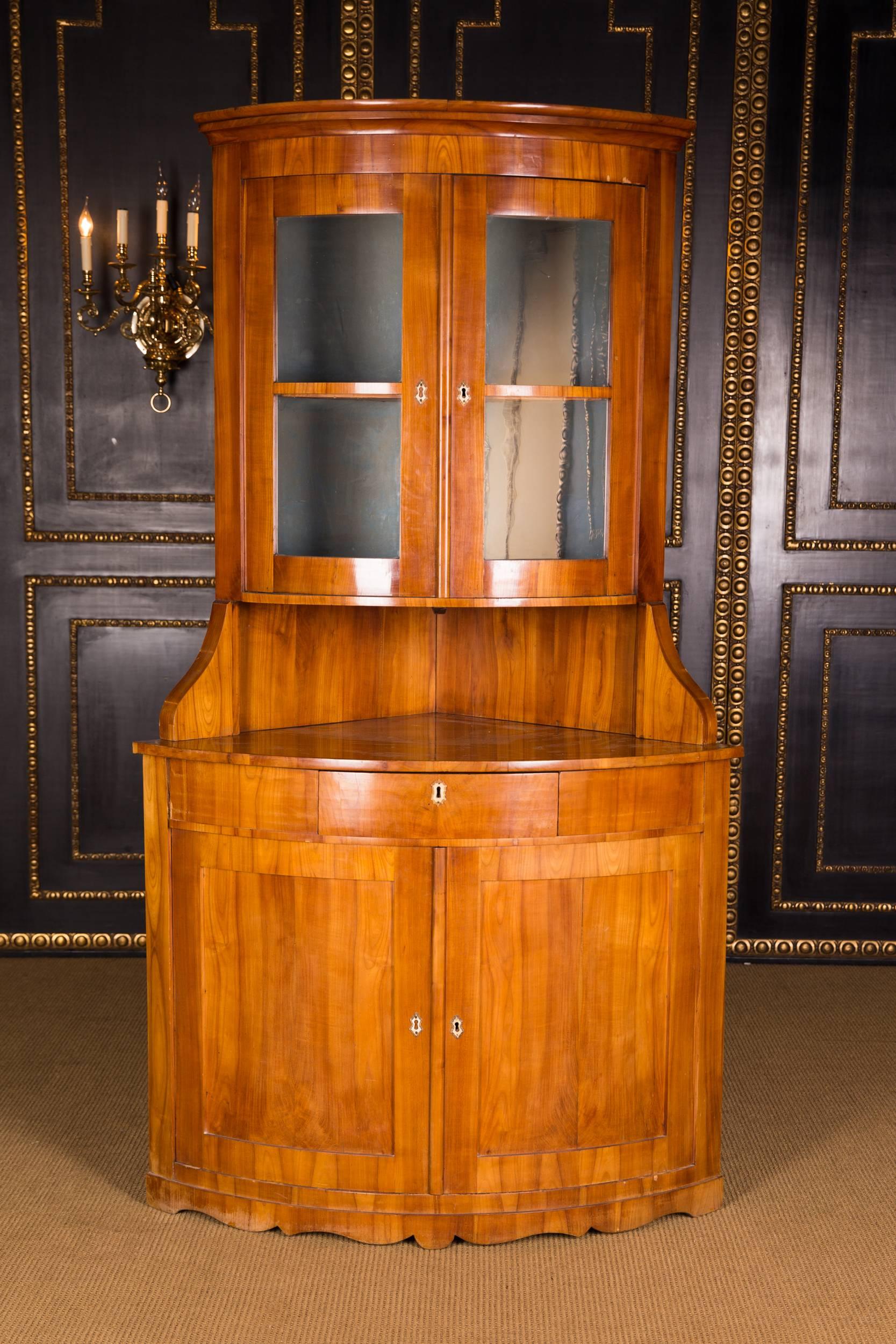 Cherry on pinewood. The corner vitrine is in an unrestored condition with a wonderful warm patina grown over decades. Such Biedermeier corner showcases in cherry are quite rare.
   