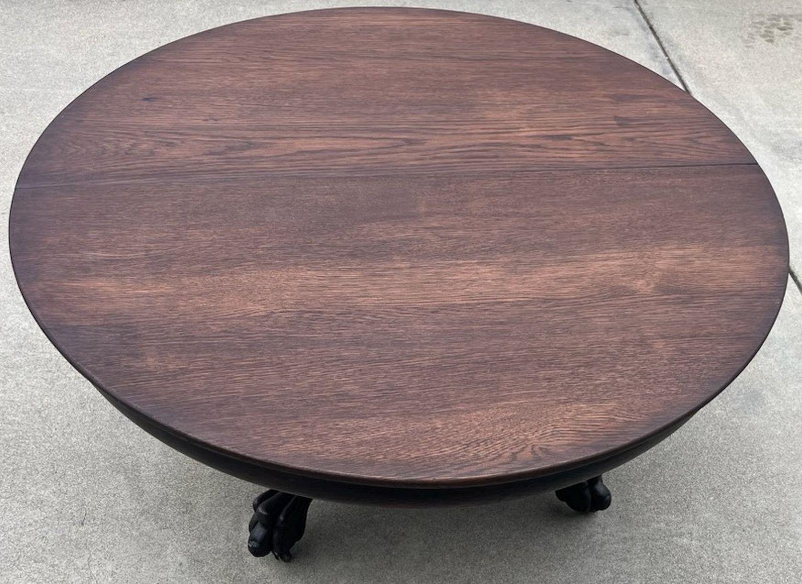 This cool round pedestal coffee table has the original cast iron casters below the hand-carved claw feet. Some call them tiger paw feet and is in great condition. The top is a two board top that clearly had additional leaf's at one time. It is so