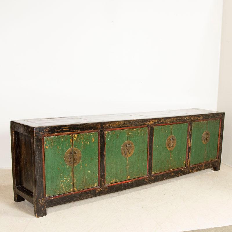 This stunning long Chinese console draws ones attention to the original green painted doors with simple red trim. The hand-buffed lacquer finish compliments the many areas where the paint was rubbed and worn down to the natural elm wood below. The