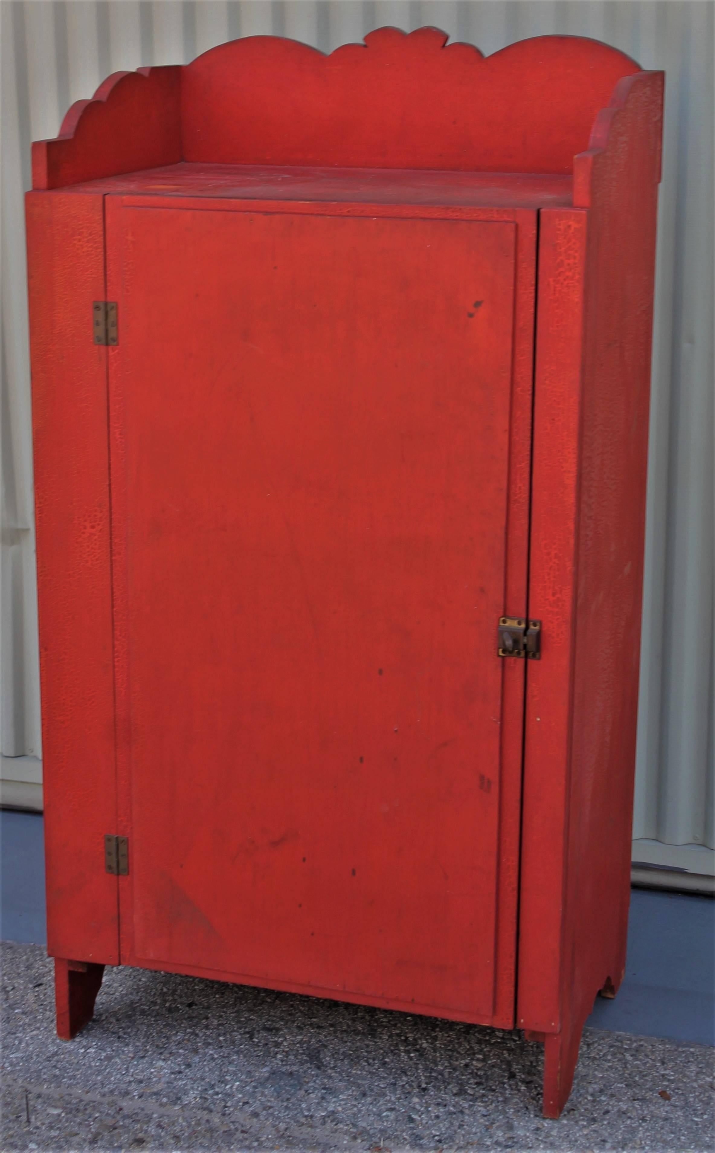 This beautiful 19th century tomato red / orange one door wall cupboard has one door and many shelf's inside. Fancy cut-out and nice details. This is in very good condition with a wonderful alligatored painted surface.